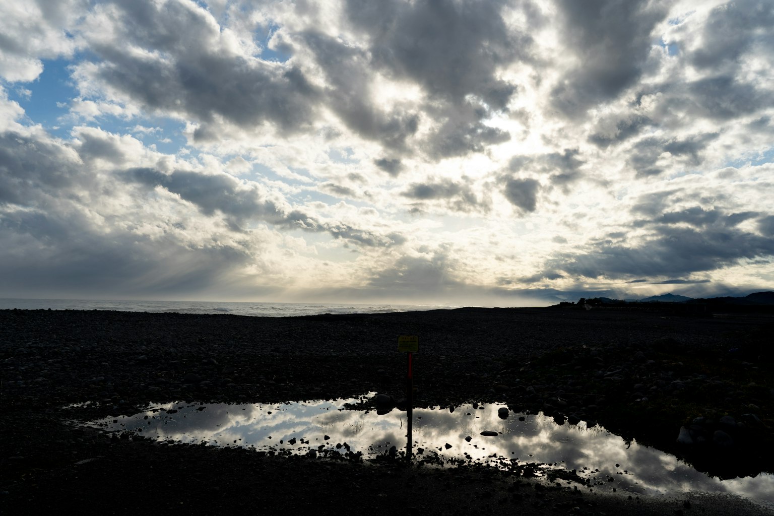 Cloudy sky reflecting on a calm pond during sunset