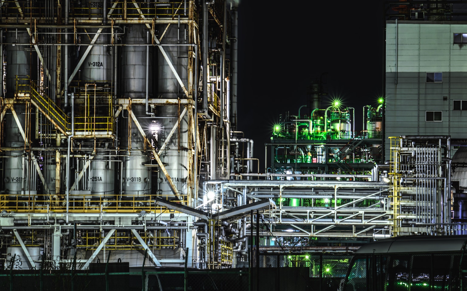 Scène industrielle nocturne avec de grands réservoirs de stockage et des pipelines illuminés