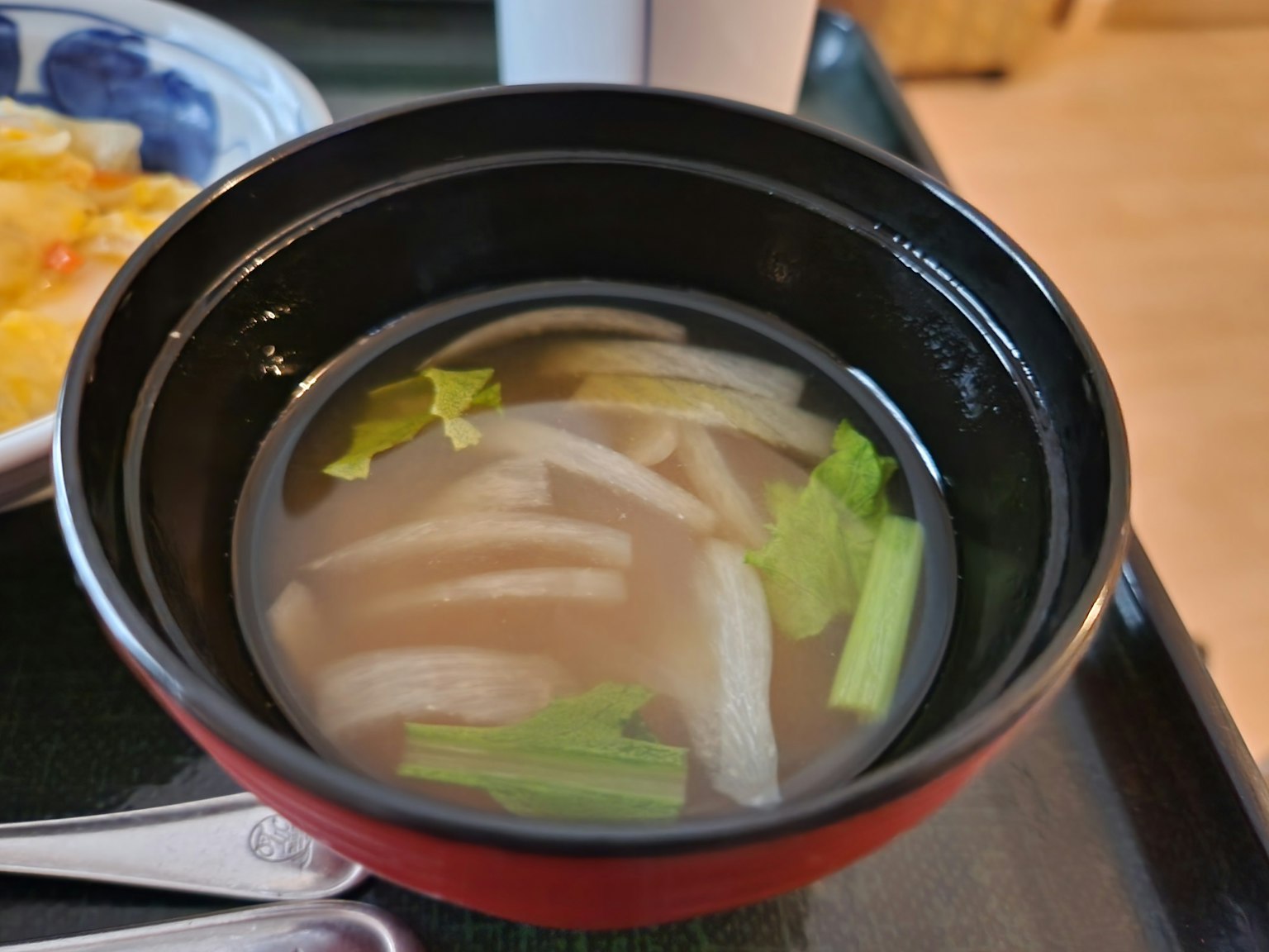 Soupe claire dans un bol noir avec des légumes tranchés