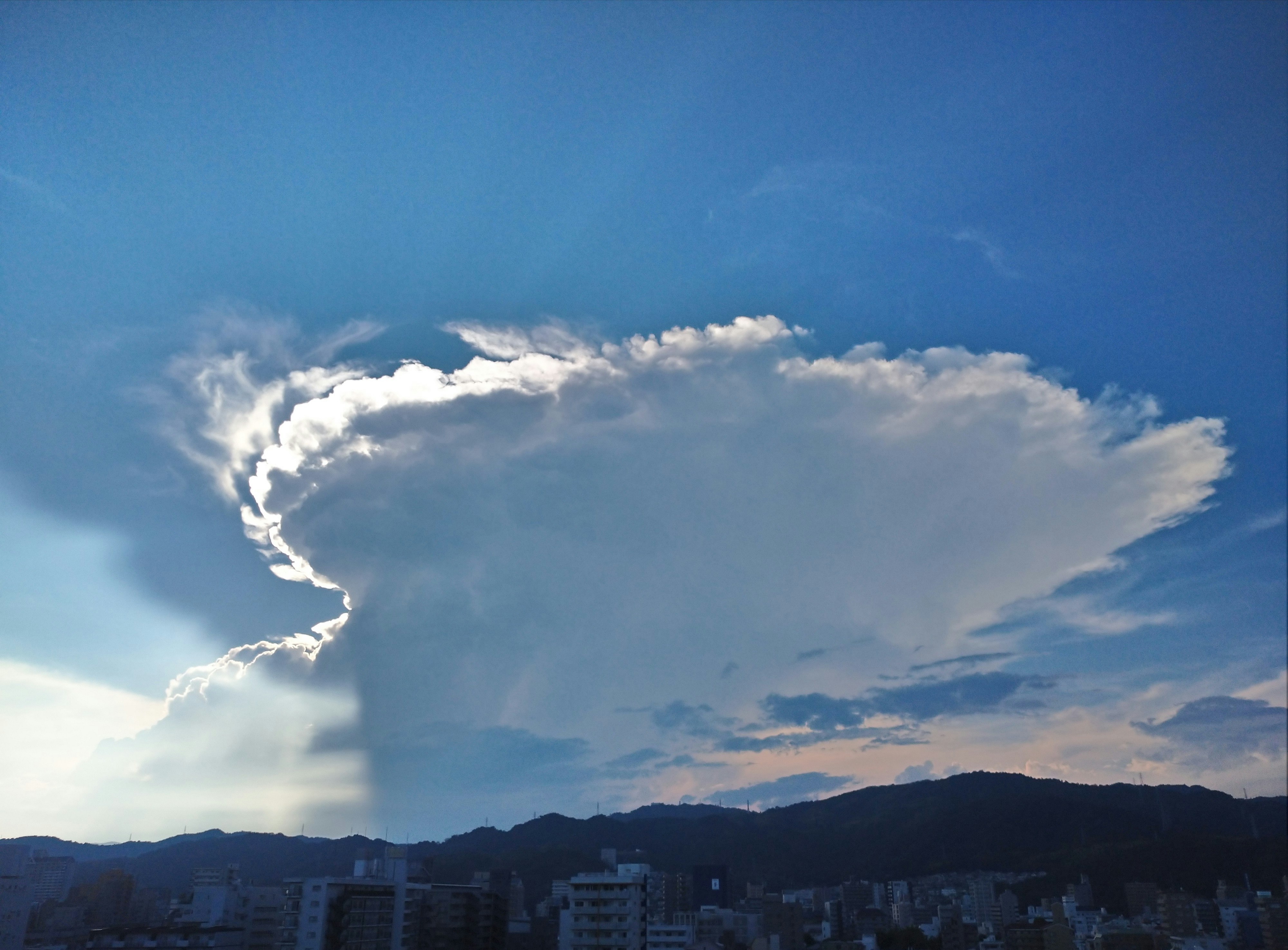 夕焼けの空に浮かぶ入道雲のような雲と街並み