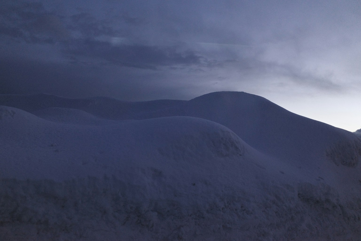 Silhouette di colline coperte di neve sotto un cielo scuro