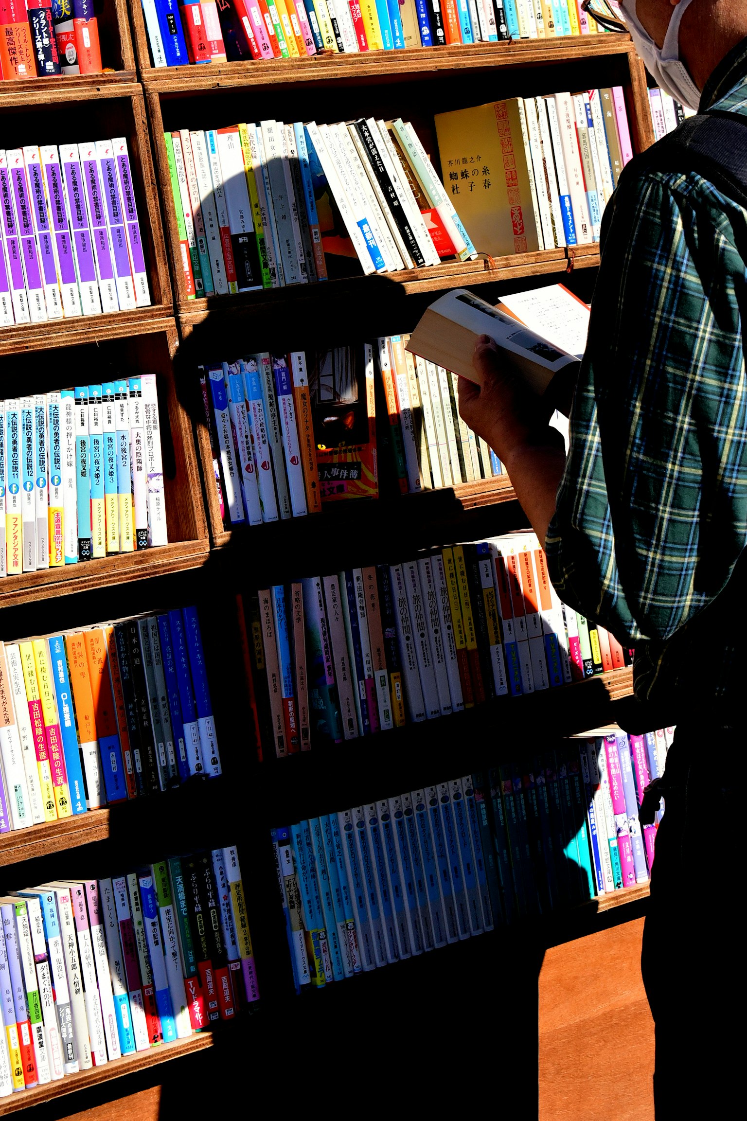 本を手に持つ人が本棚の前に立っているシーン 書籍が整然と並んでいる