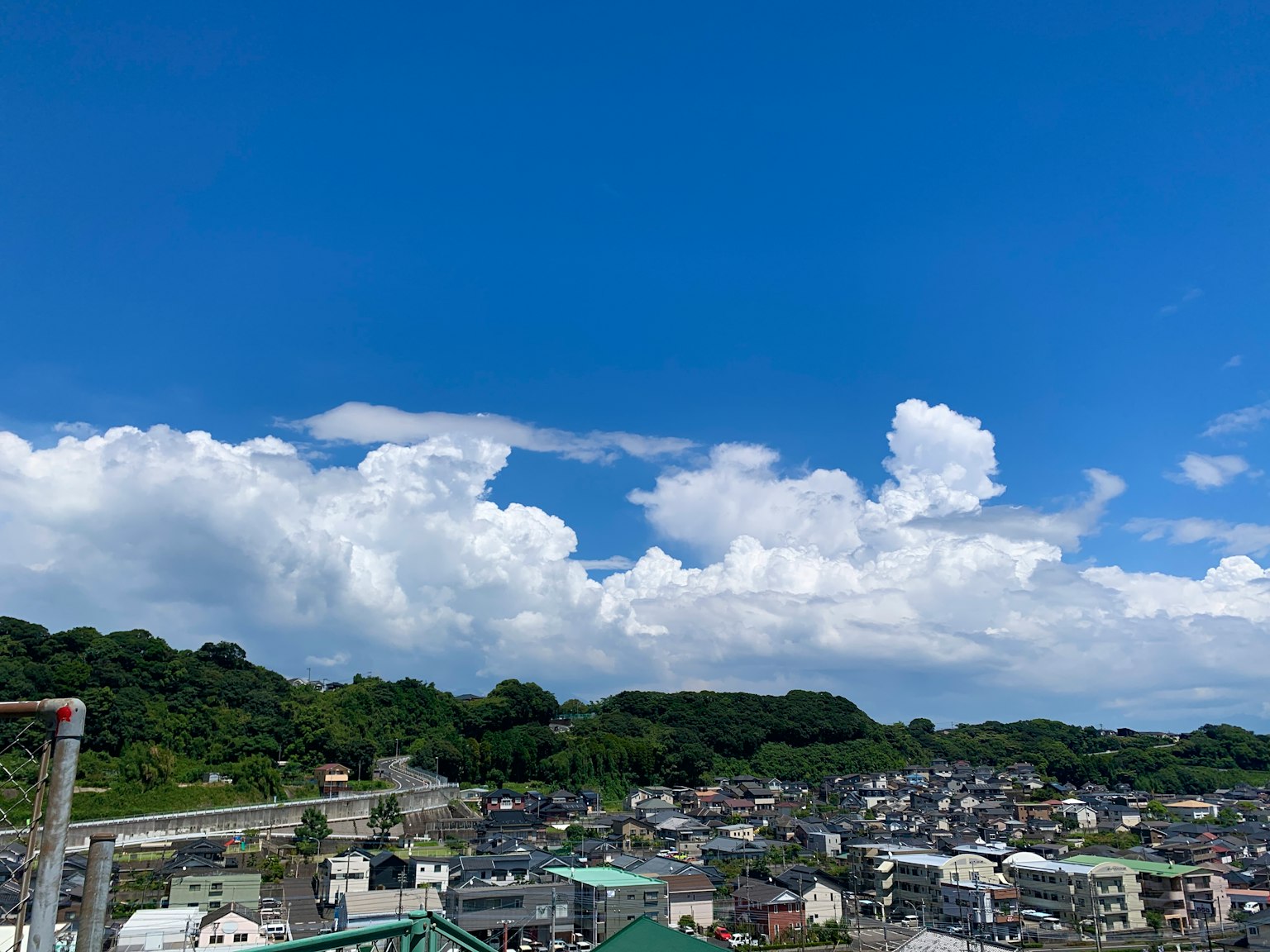 A landscape featuring blue sky and white clouds over a residential area