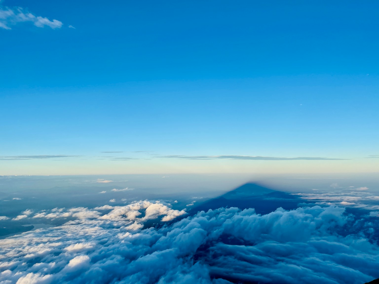 Sombra de una montaña sobre las nubes con un cielo azul claro
