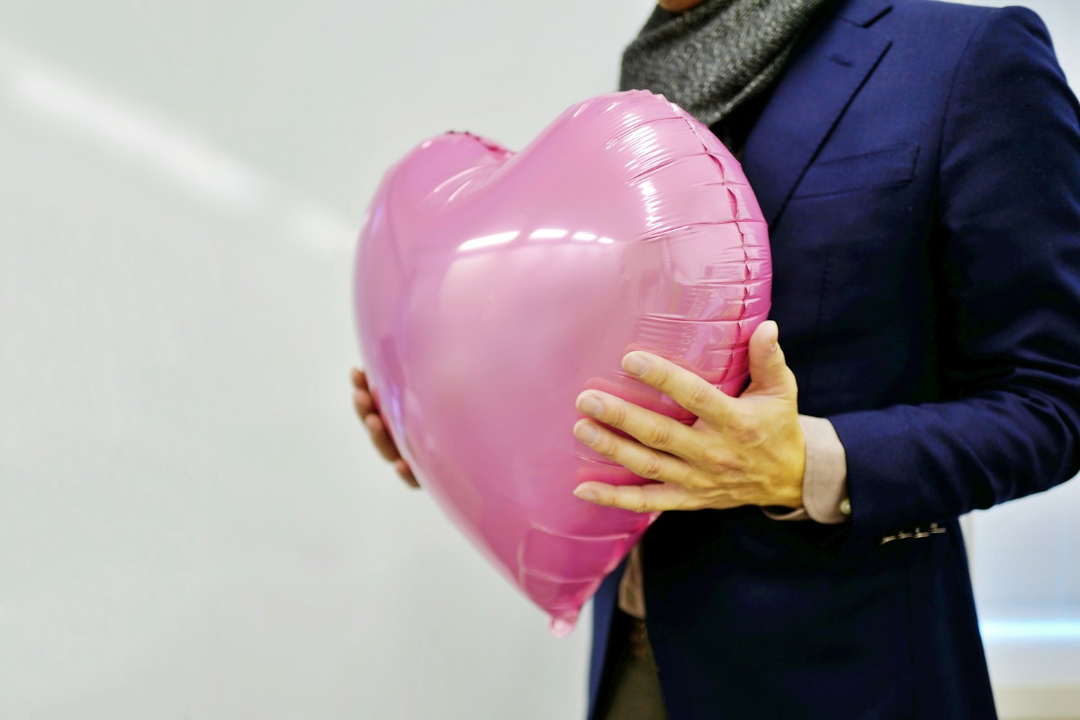 Ein Mann hält einen rosa herzförmigen Ballon