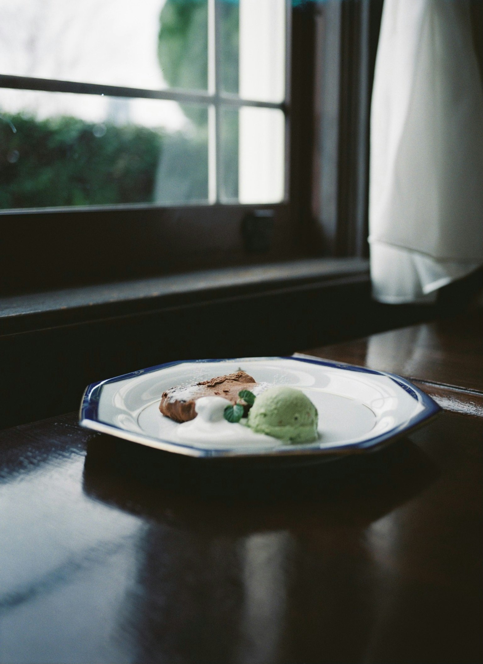 Un plato con helado y galletas cerca de una ventana