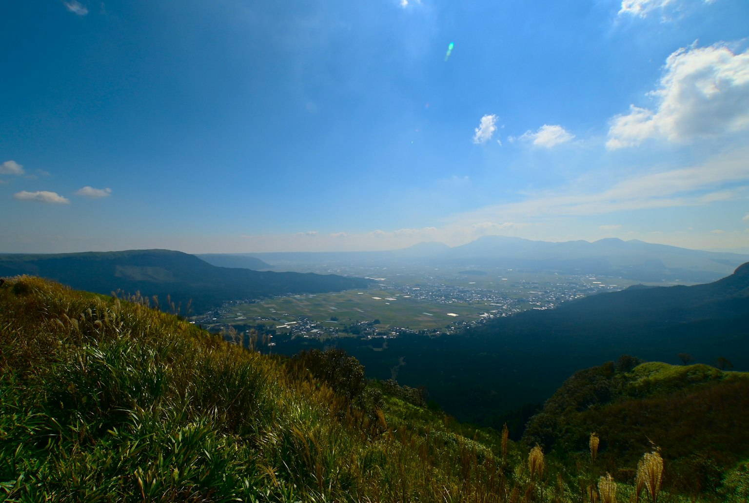 Vista panoramica di montagne e valli sotto un cielo azzurro con nuvole
