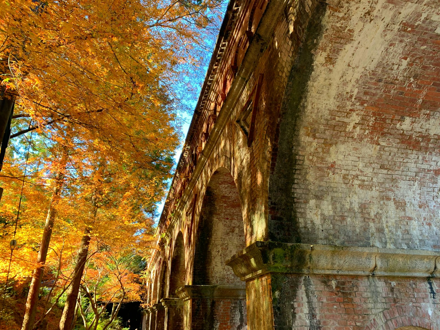 Antiche arcate in mattoni circondate da fogliame autunnale vibrante