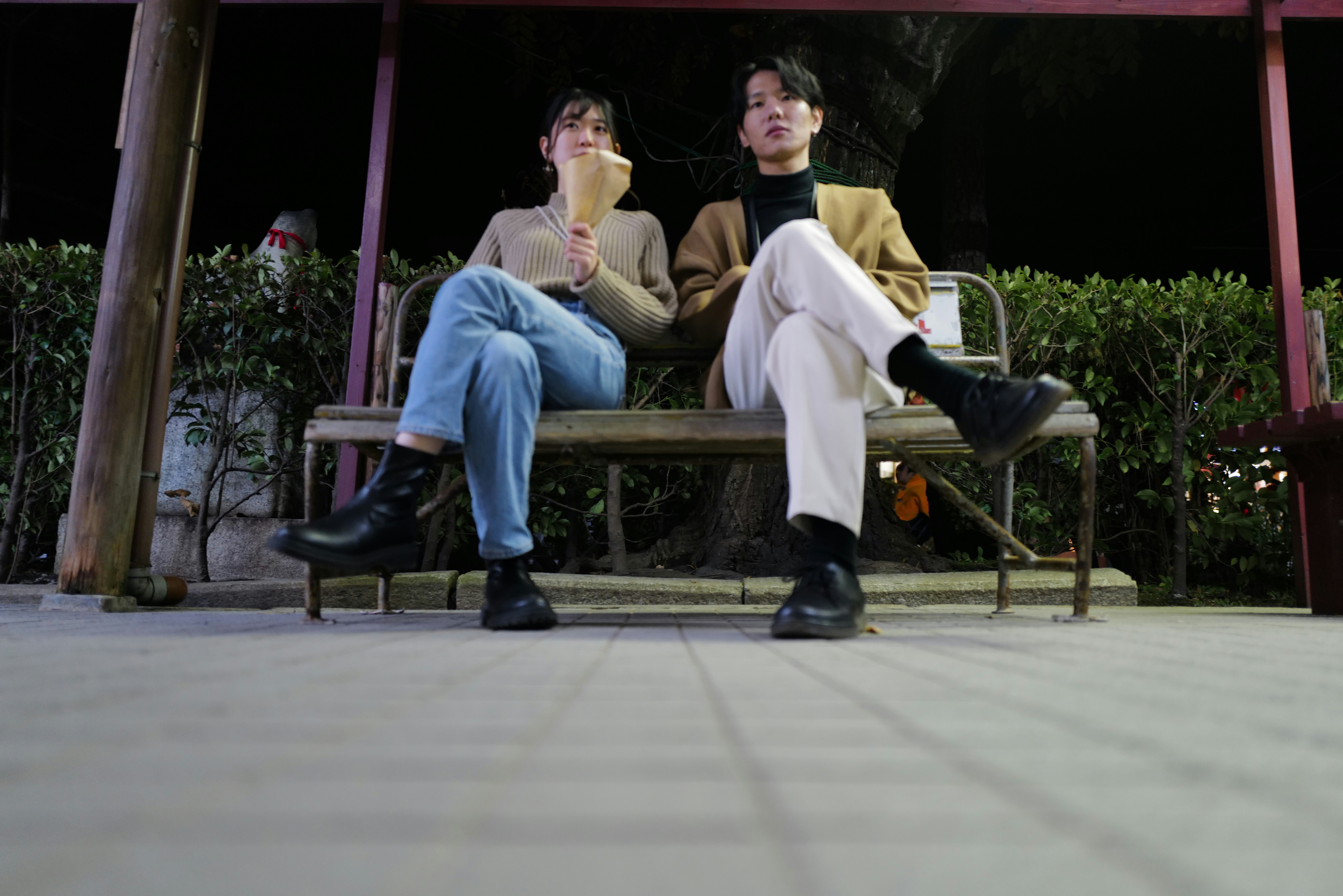 夜のベンチに座る2人の若者