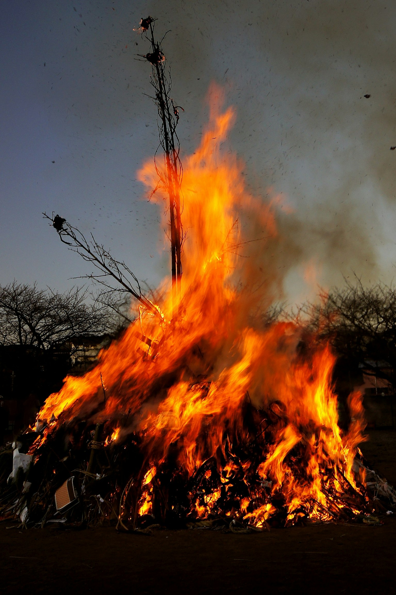 Ein loderndes Lagerfeuer mit Flammen und Rauch, der in den Abendhimmel aufsteigt