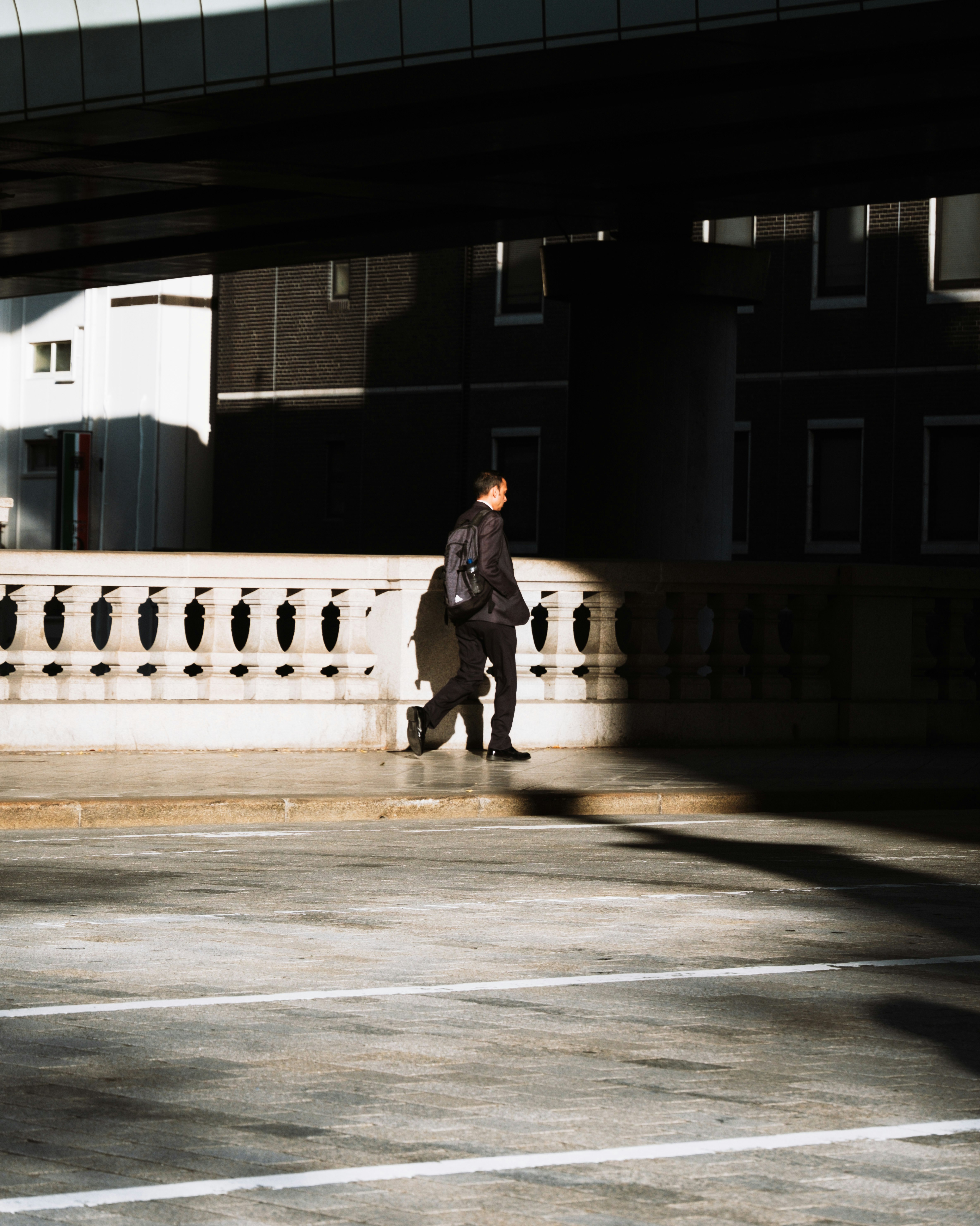 man in a suit walking under an arcade colonnade