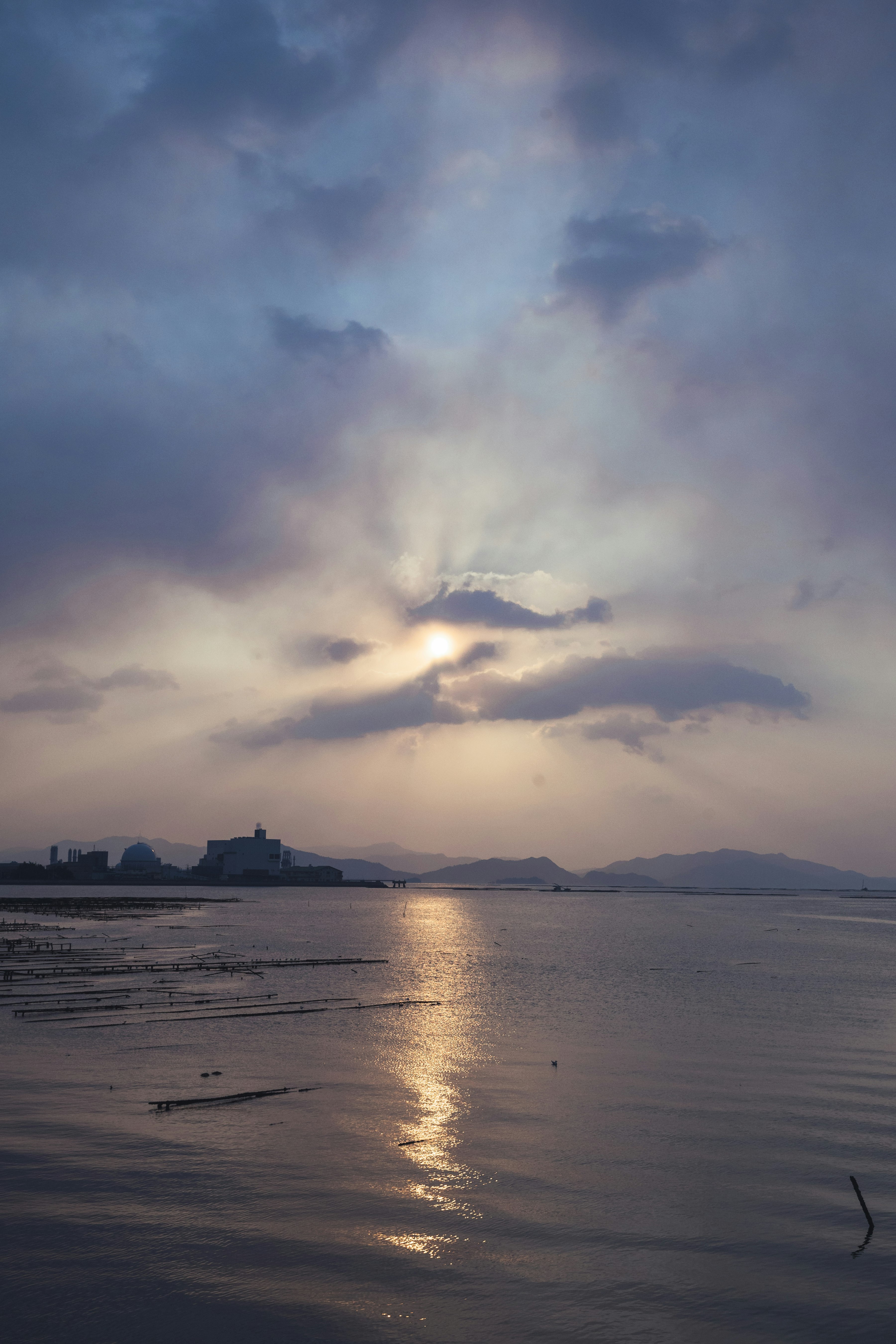 夕暮れの海辺と水平線に浮かぶ山影のある風景