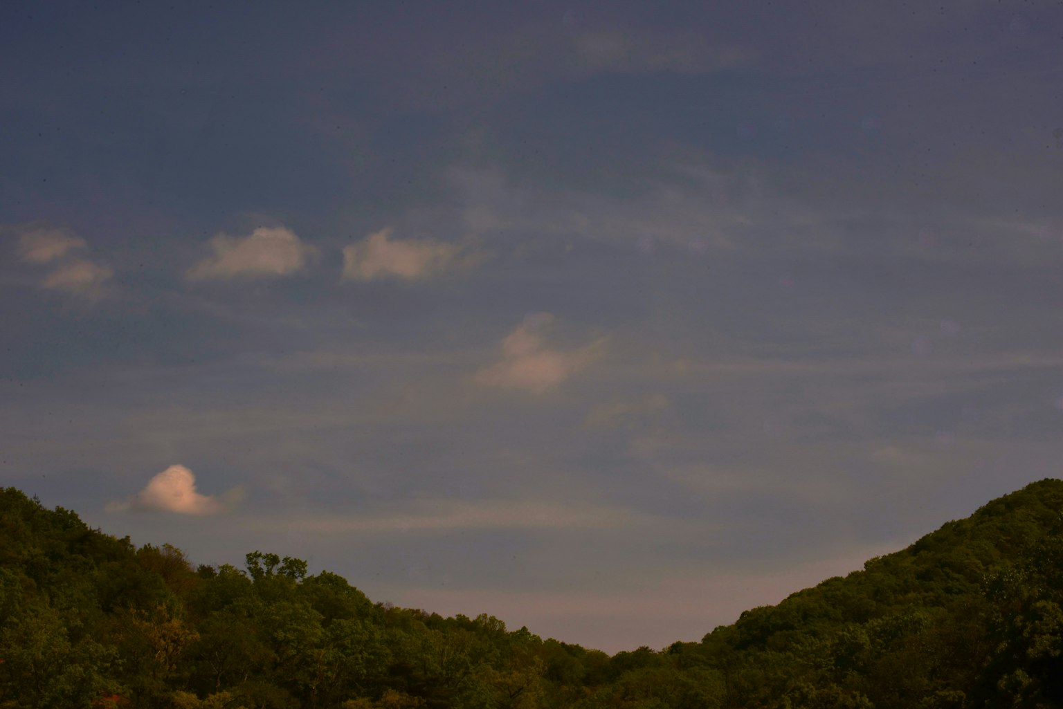 Silhouette de montagnes sous un ciel bleu avec des nuages épars