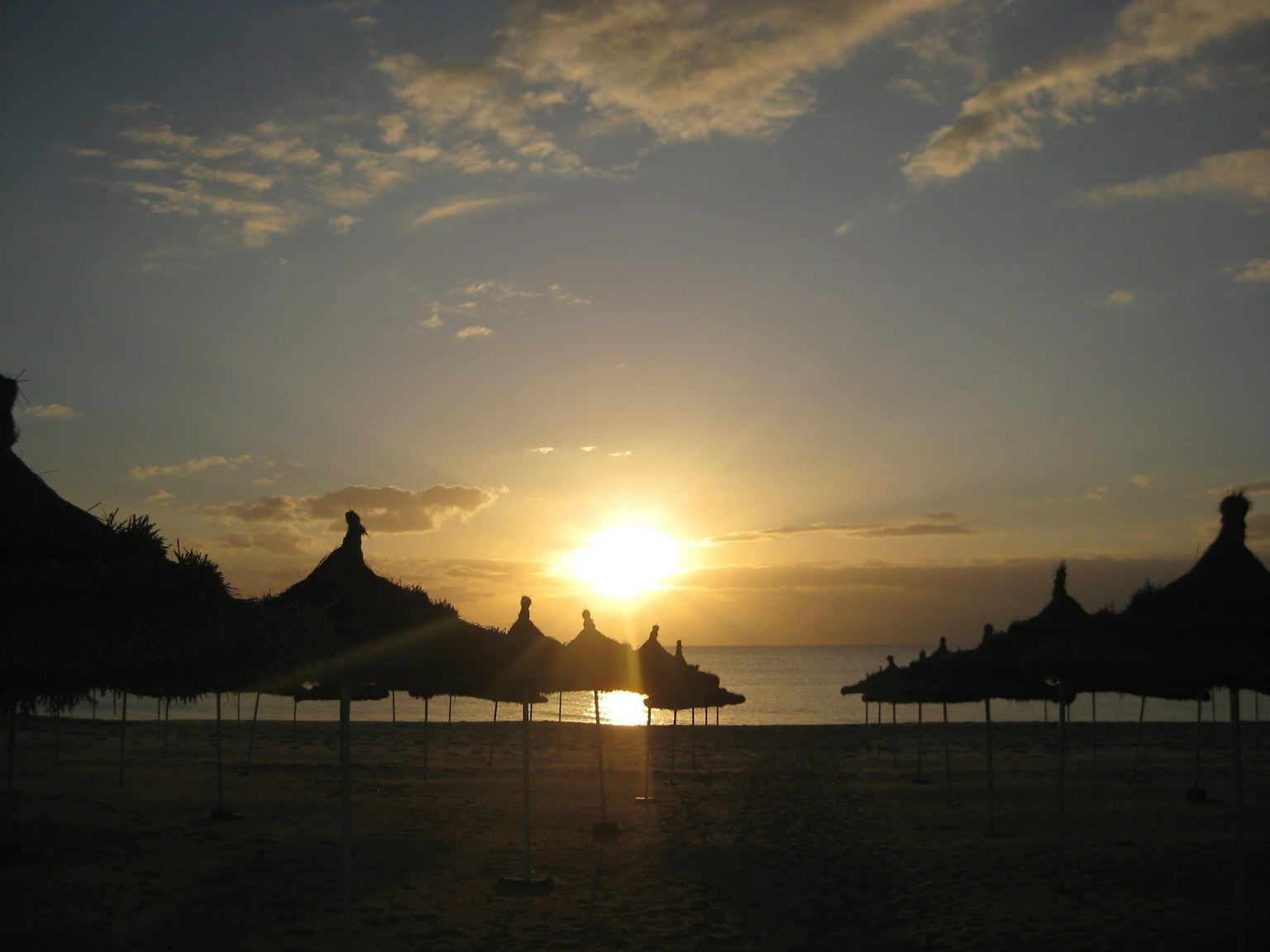 Sonnenuntergangsszene am Strand mit Silhouetten von Sonnenschirmen
