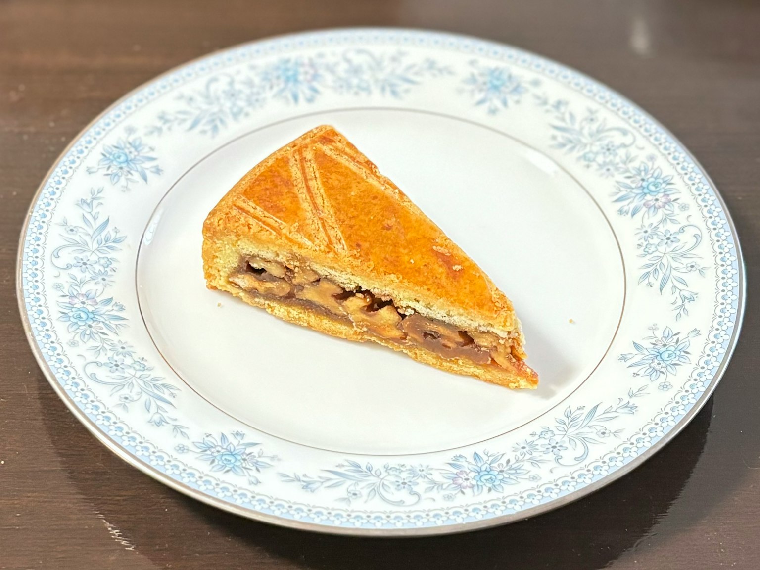 Fetta di torta su un piatto decorativo con fiori blu