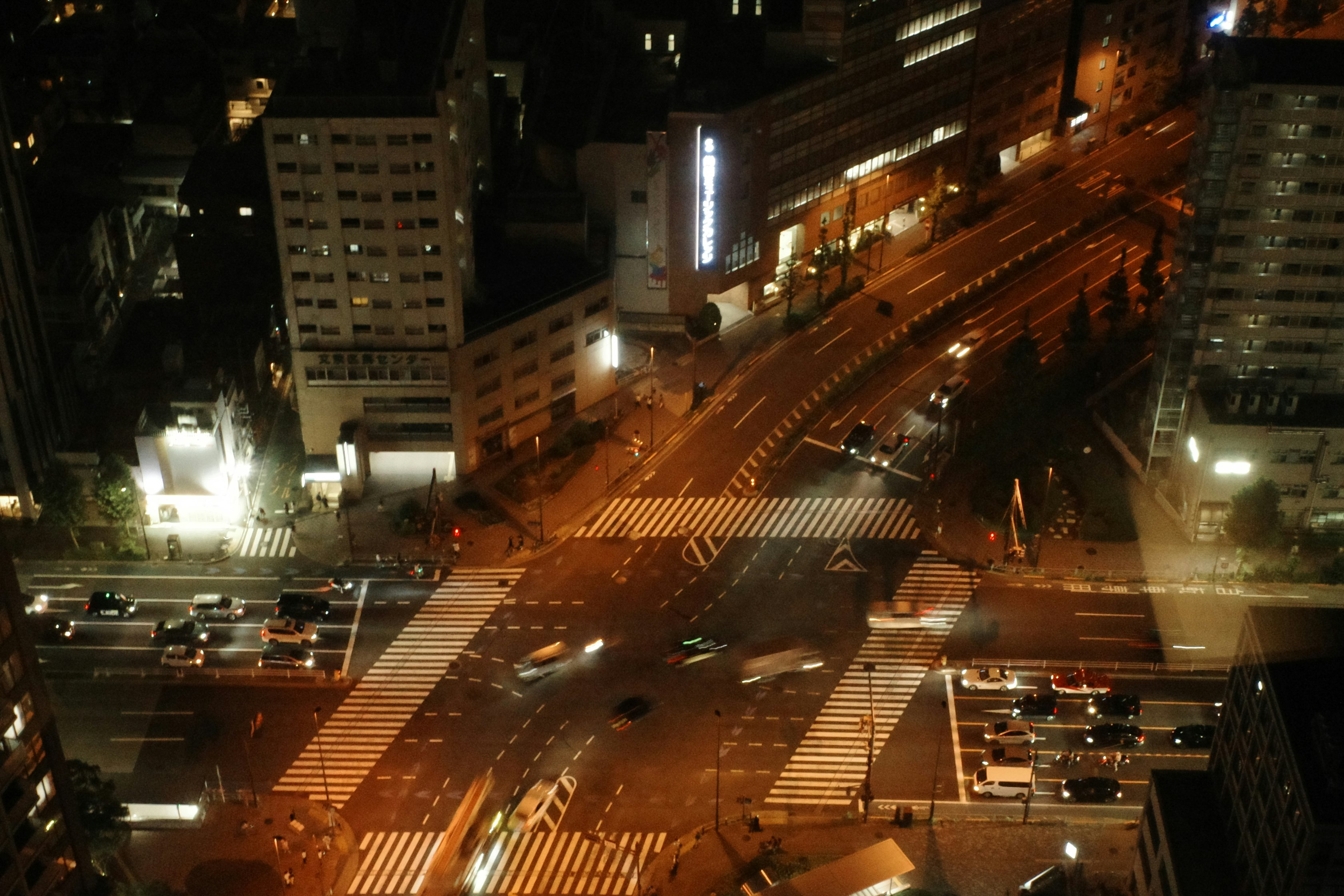 夜の大通りを走る車と交差点の横断歩道