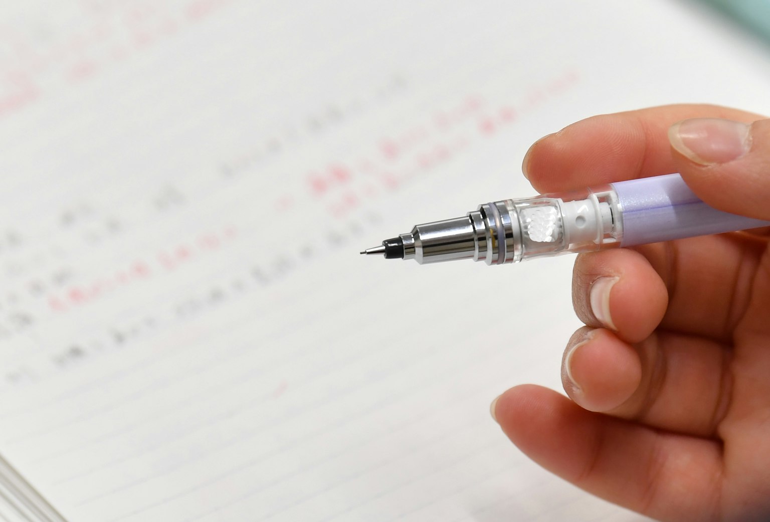 Una mano che tiene una penna sopra una pagina di quaderno con testo scritto