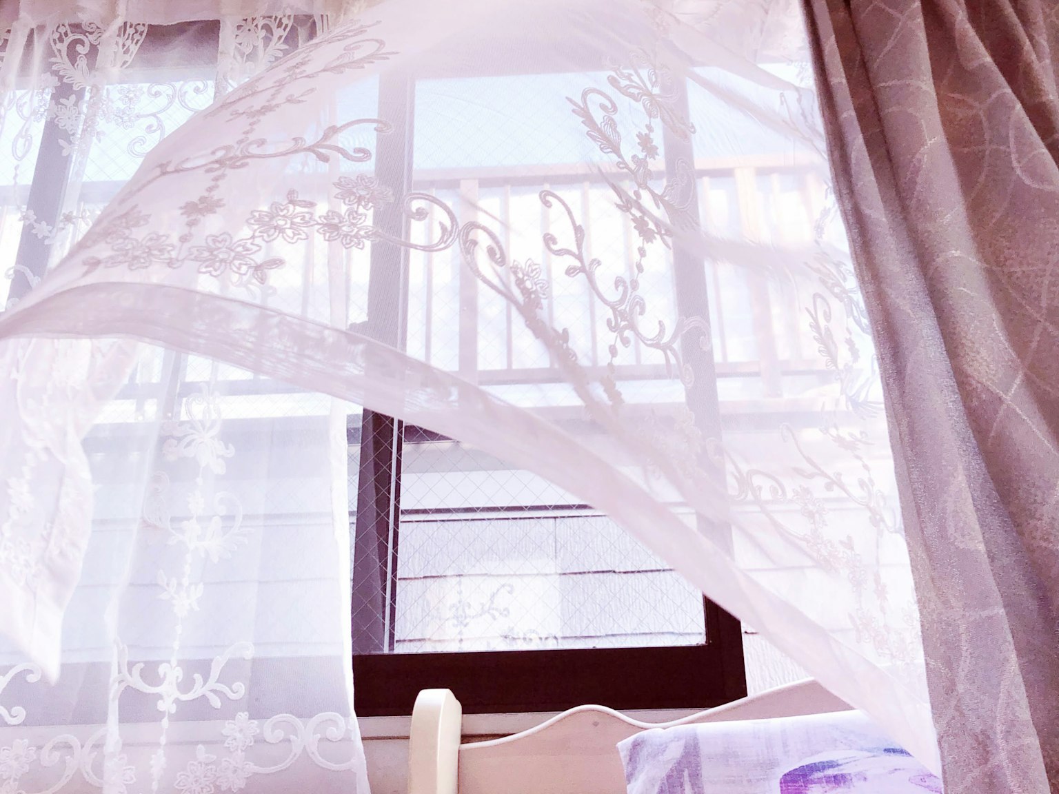 Durchsichtiger Vorhang, der vor einem Fenster weht, mit sanftem Licht, das in den Raum strömt