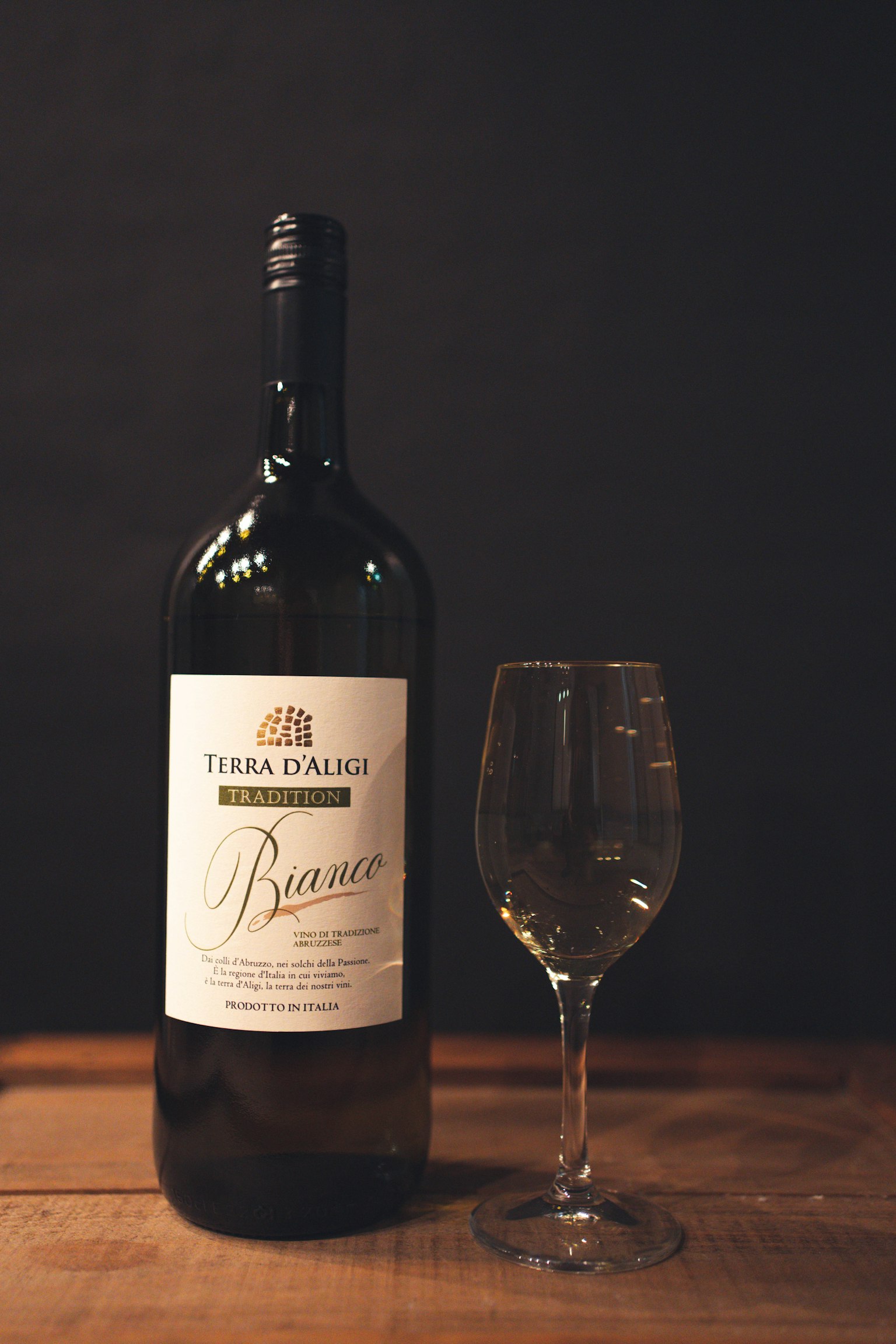 Une grande bouteille de vin à côté d'un verre sur une surface en bois