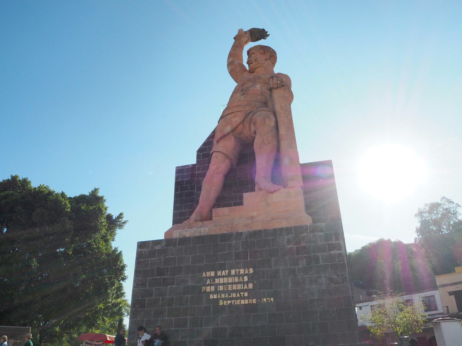 Gran estatua que se erige bajo un cielo azul con sol brillante