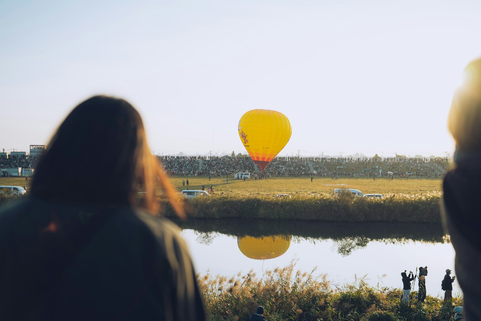 Orang-orang melihat balon udara kuning mengapung di atas sungai