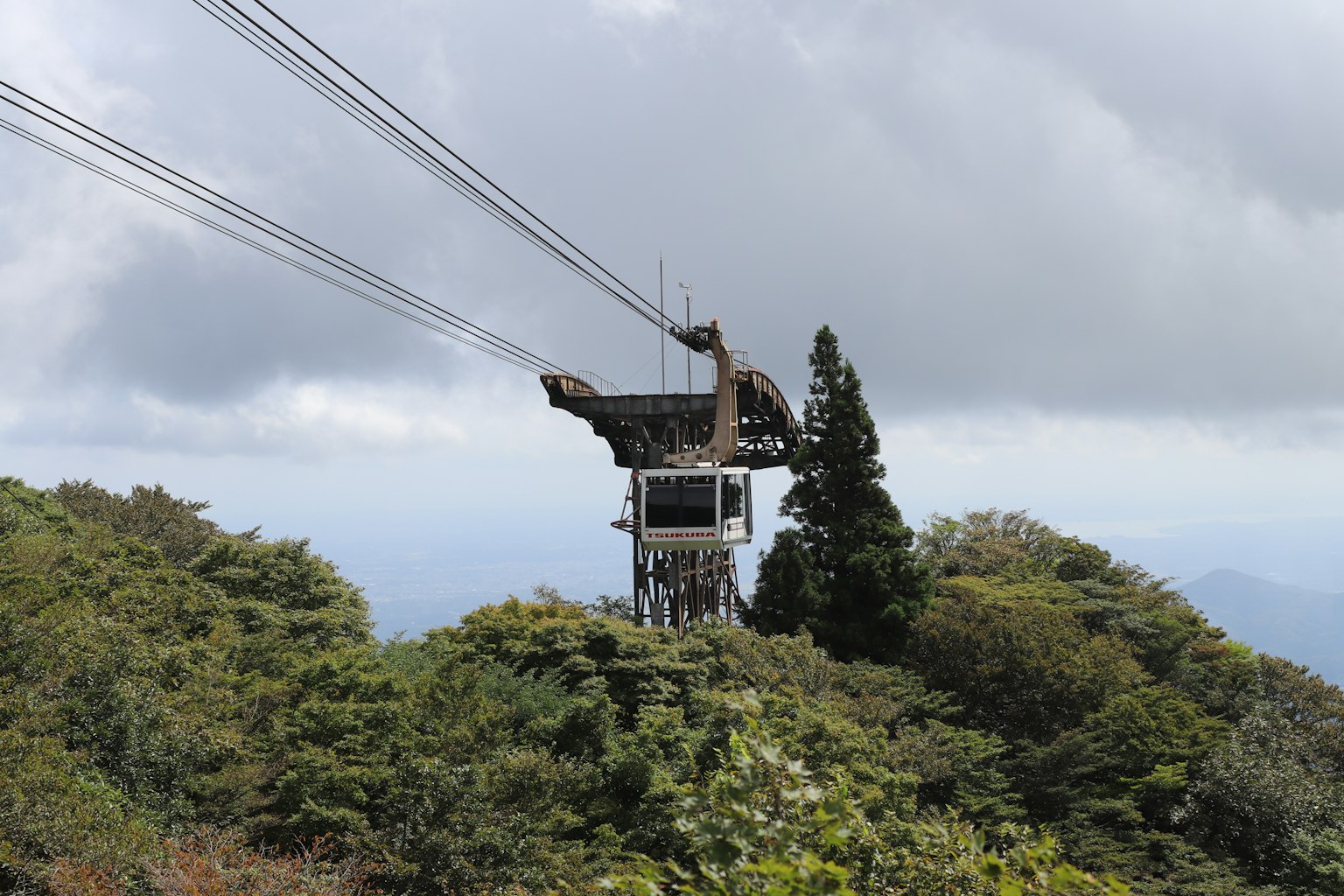 A cable car station on a mountain surrounded by green trees