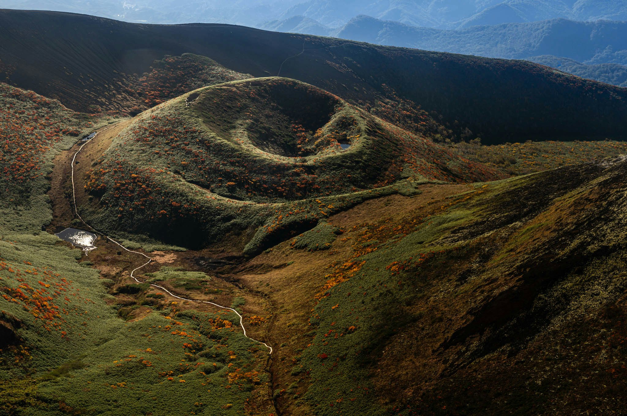 valle di montagna con sentiero tortuoso tra creste scoscese