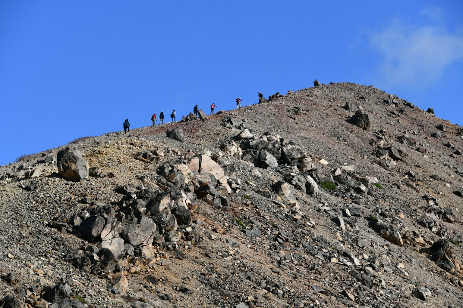 Pendaki di puncak gunung di bawah langit biru