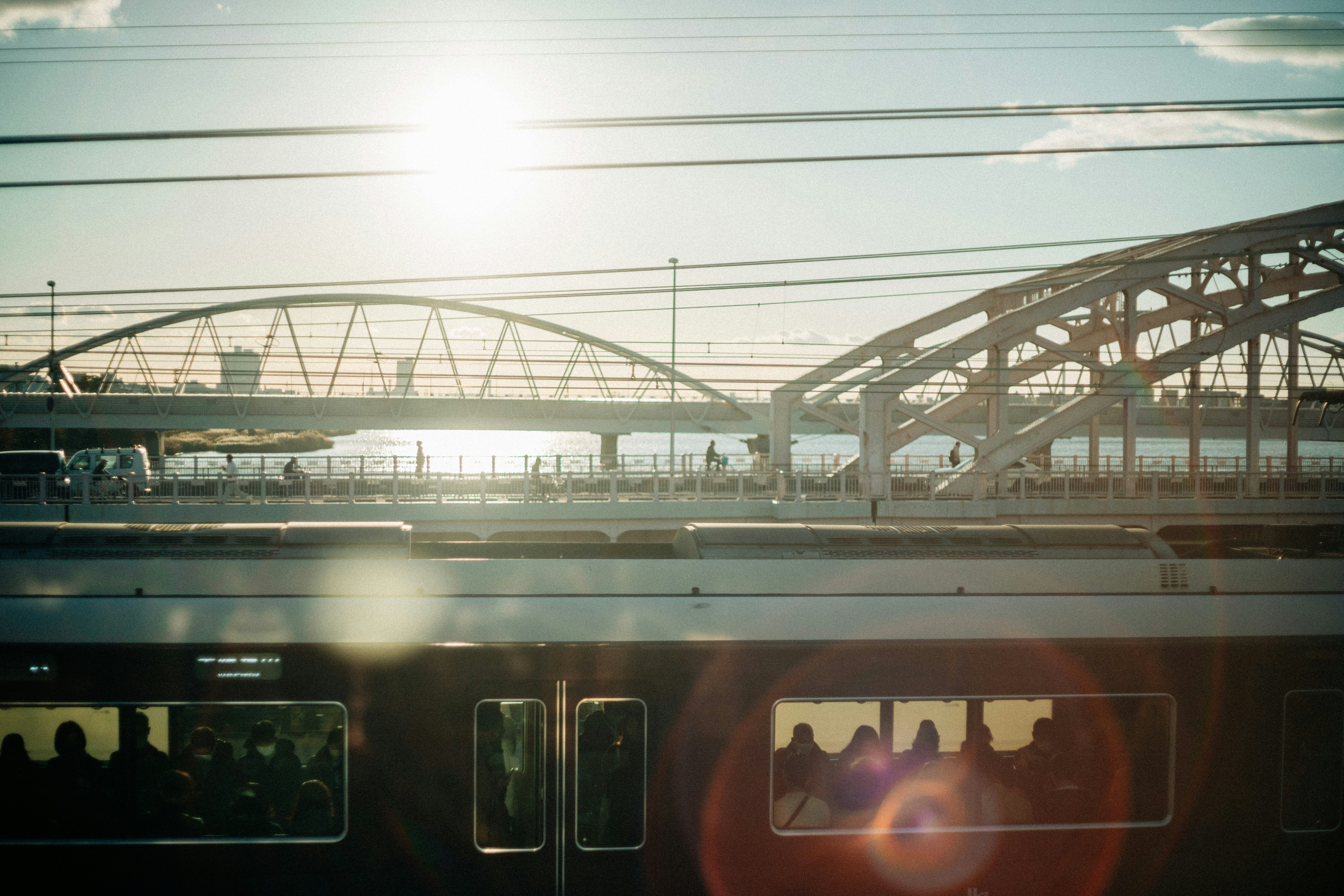 Train passing by a riverside with a steel bridge