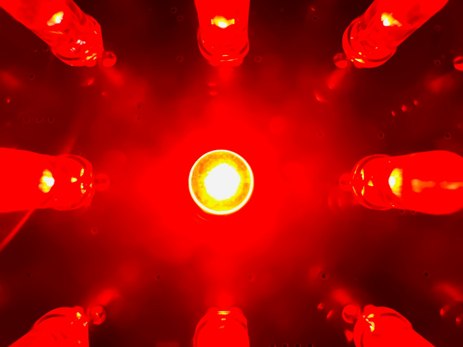 Lumière centrale brillante entourée de bouteilles rouges disposées en cercle