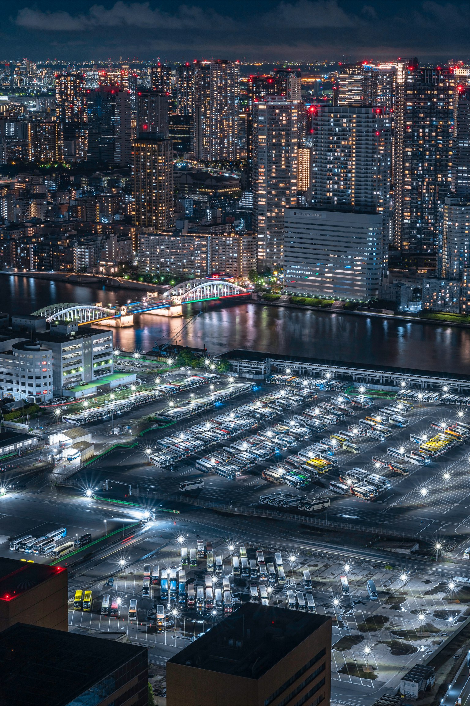 东京湾的夜景，灯光闪烁的建筑和靠近水边的停放车辆