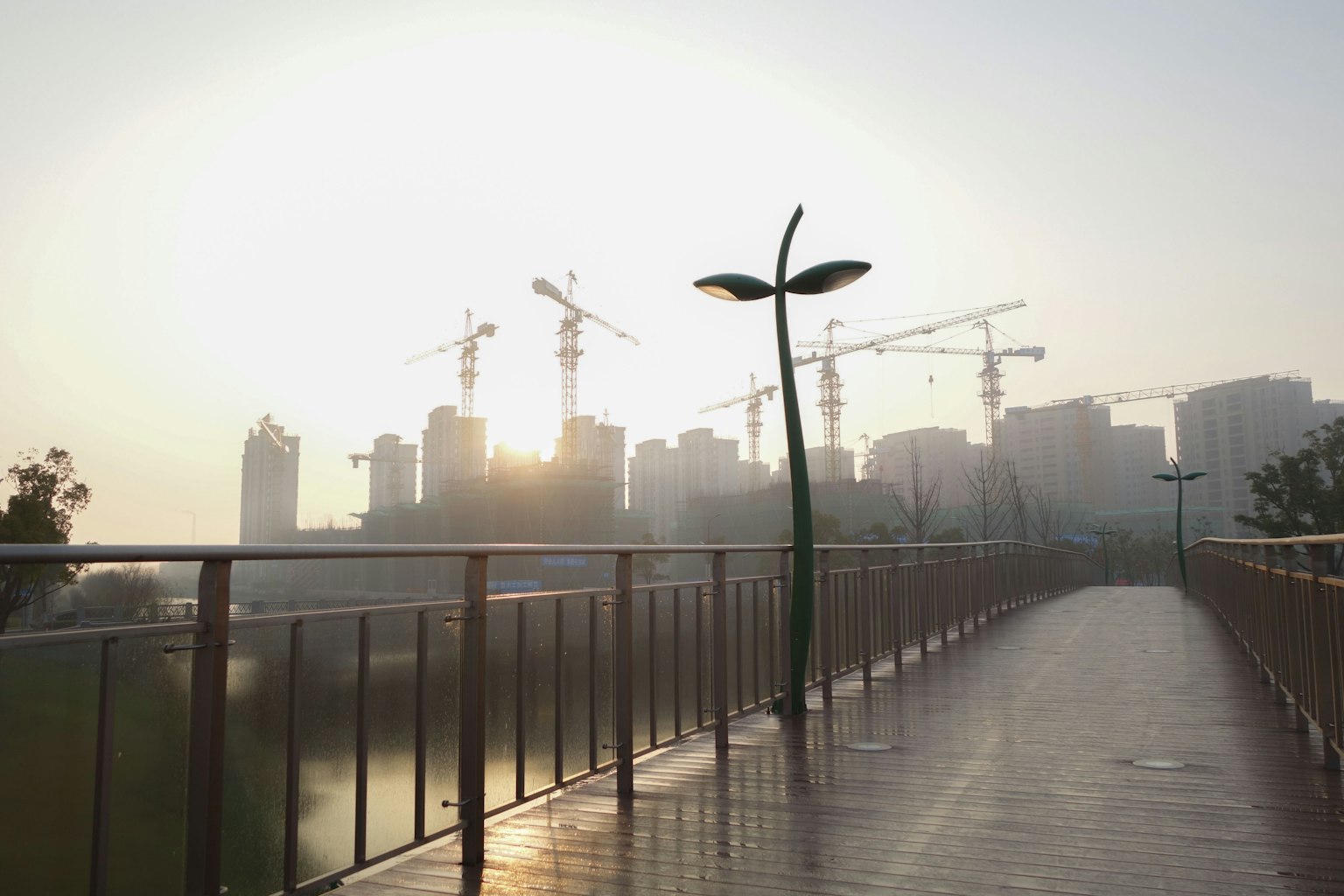 Weg mit modernen Straßenlaternen und Baukränen bei Sonnenuntergang