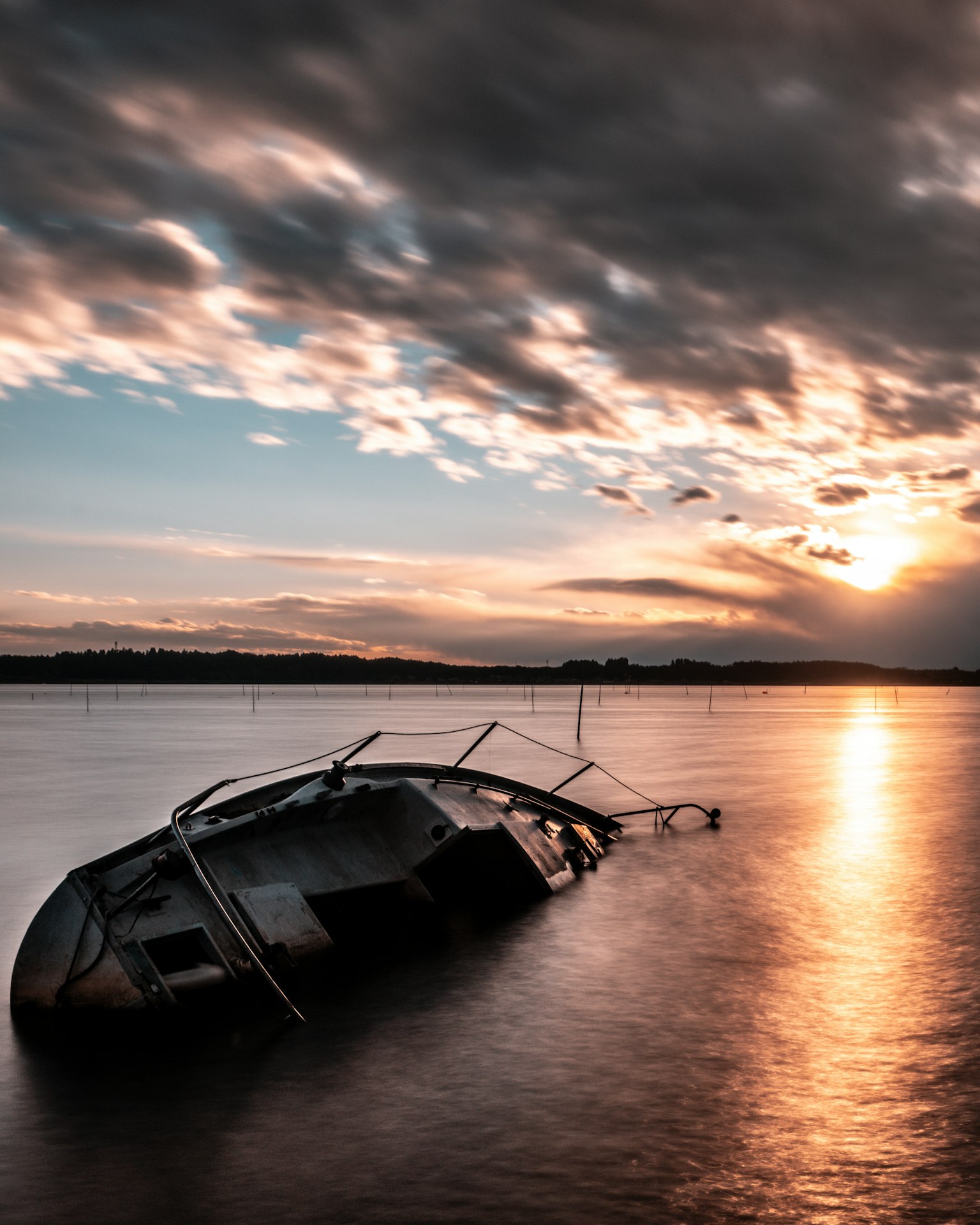 A sunken boat in calm waters during sunset