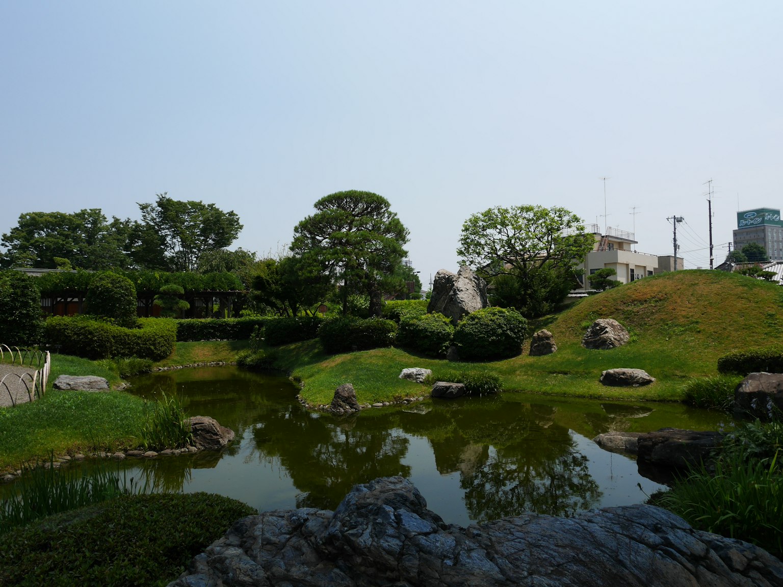 寧靜的公園景觀綠色草坪和池塘遠處可見建築
