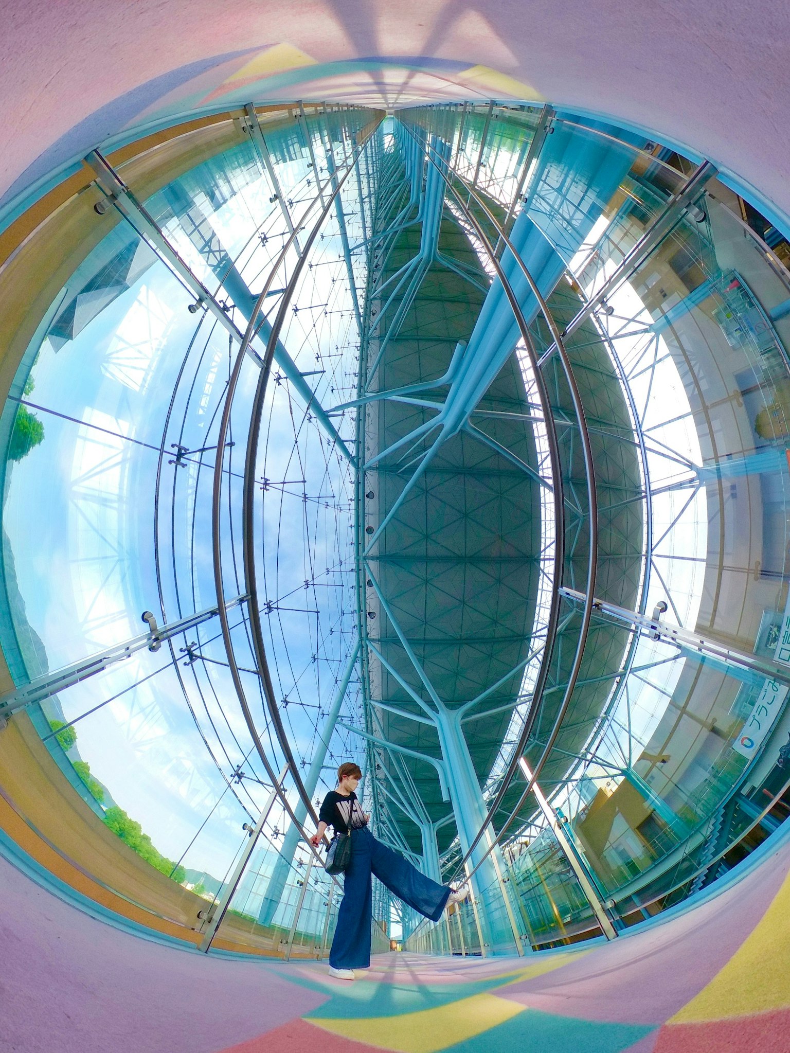 Una persona che posa in uno spazio colorato con architettura in vetro e riflessi