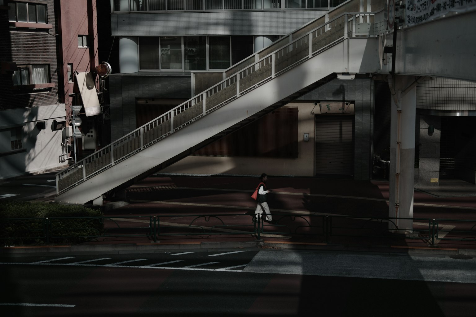 Städtische Szene mit einer Person, die auf einer dunklen Straße geht und einer Überführung