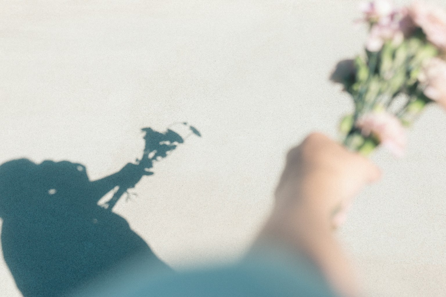 L'ombra di una persona che tiene un mazzo di fiori
