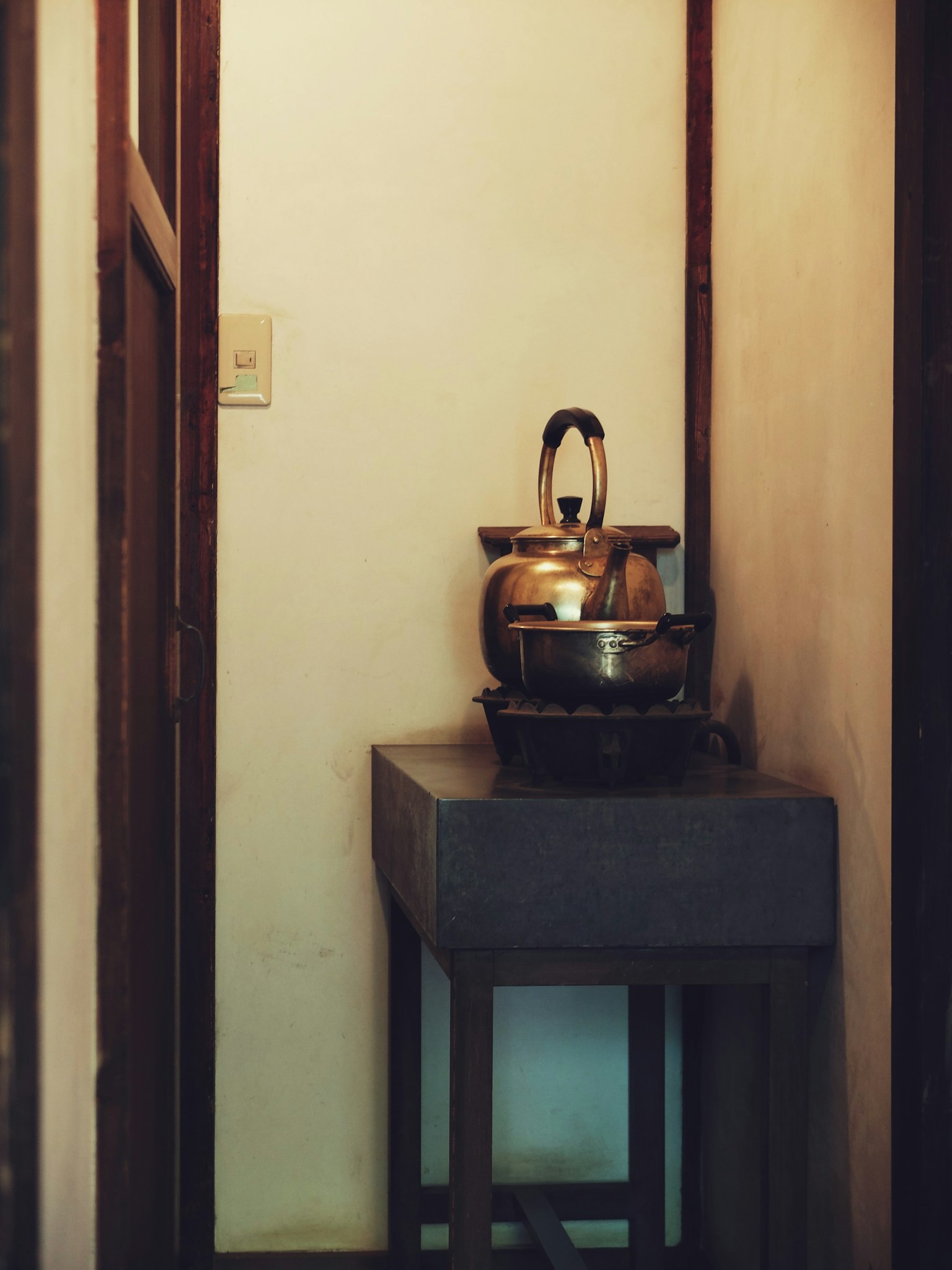 A corner of a simple kitchen featuring a silver kettle and pot