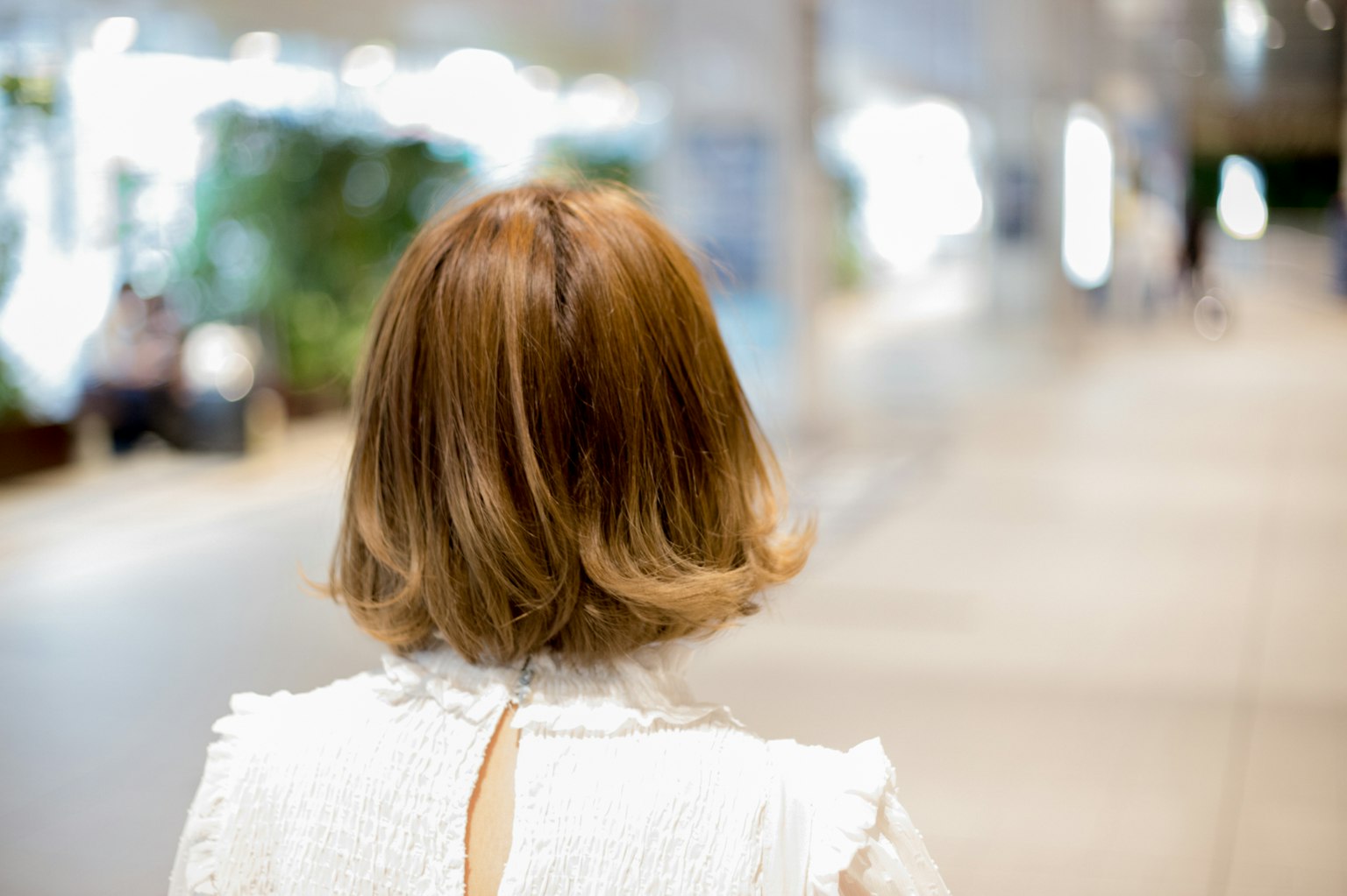 Una mujer vista desde atrás caminando en un entorno urbano brillante