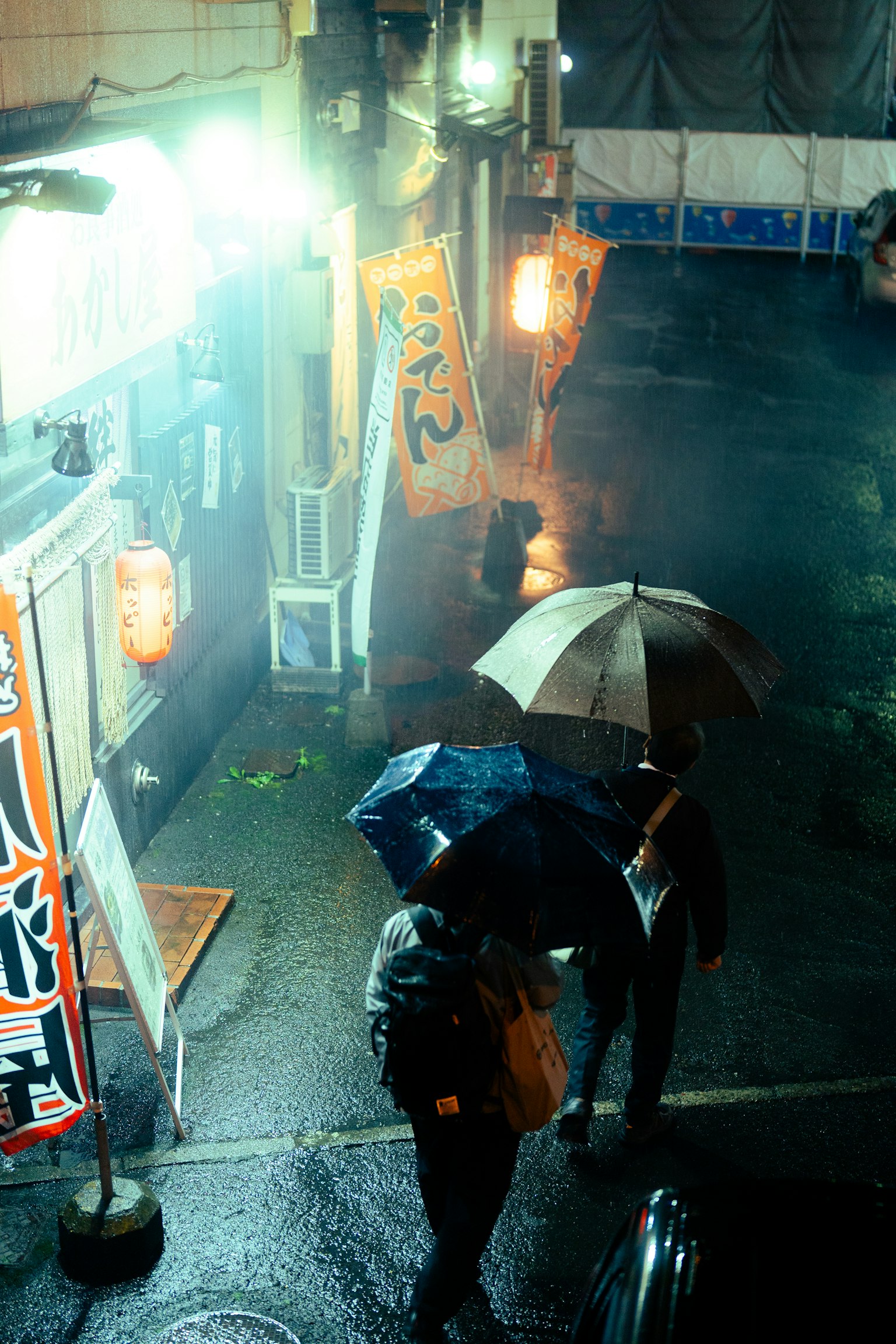 雨中撐傘的人們在明亮的街頭標誌附近