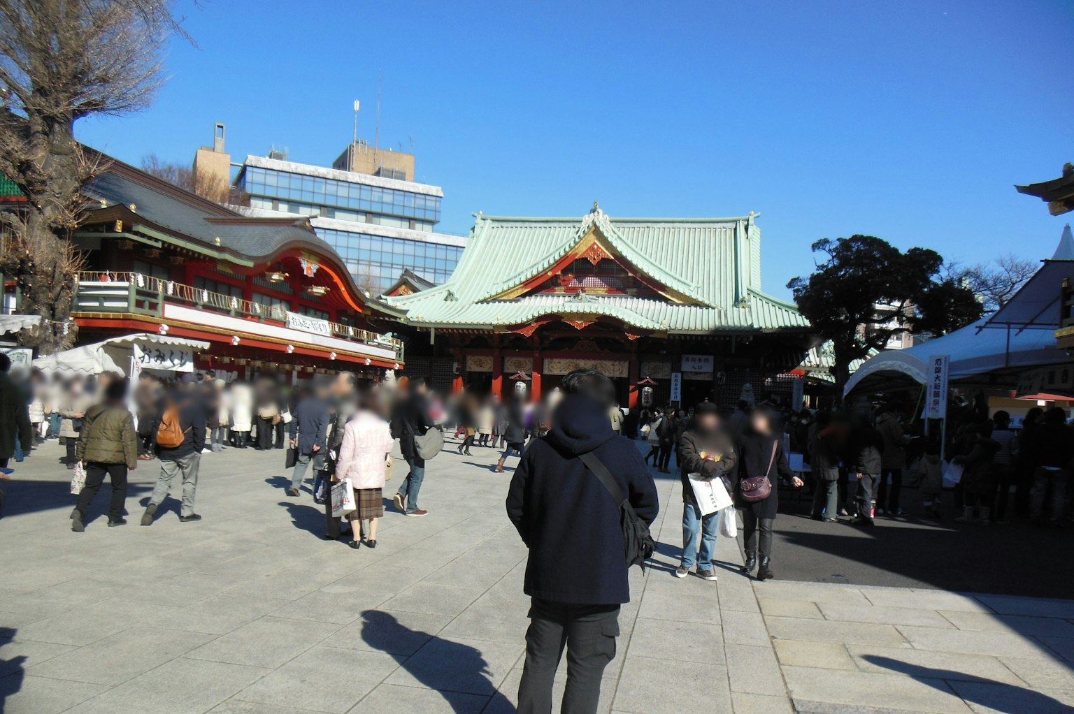 A crowded shrine plaza with people under a blue sky and traditional architecture