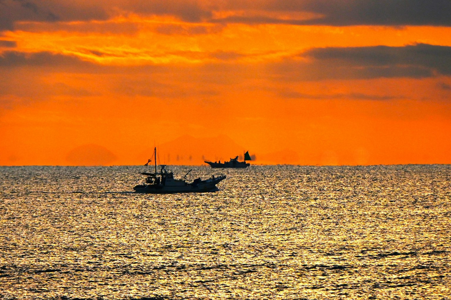 Silhouettes of fishing boats on the ocean at sunset