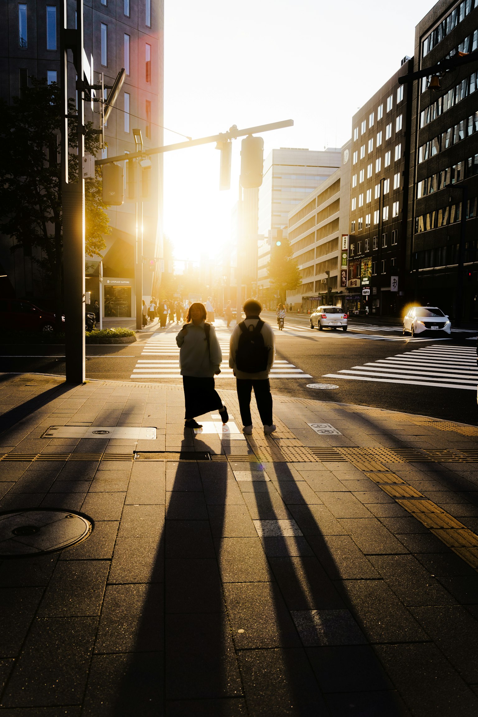 Deux personnes marchant dans la lumière du coucher de soleil avec de longues ombres dans un environnement urbain