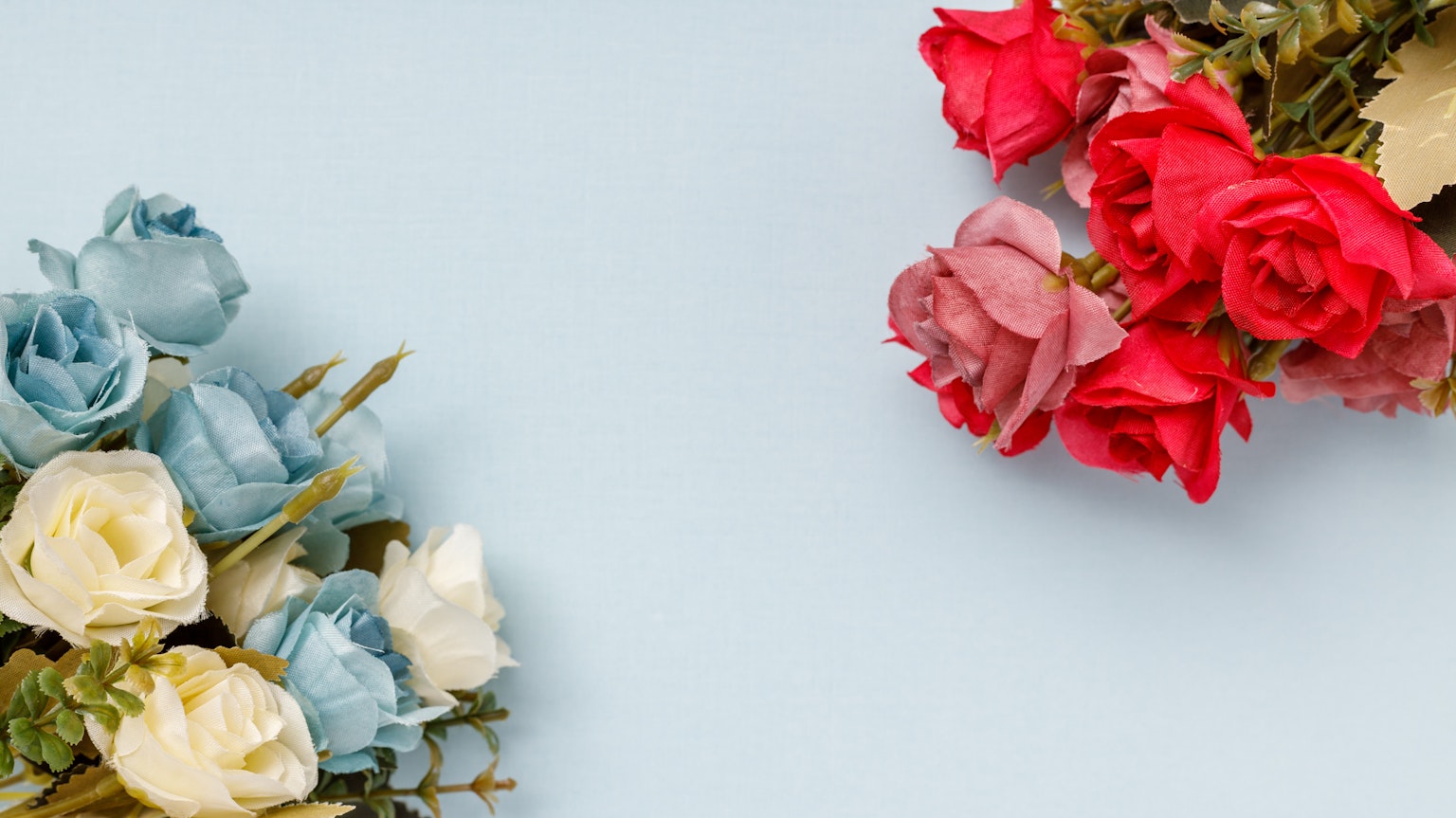 Sträuße aus blauen und weißen Rosen neben roten Rosen auf einem blauen Hintergrund