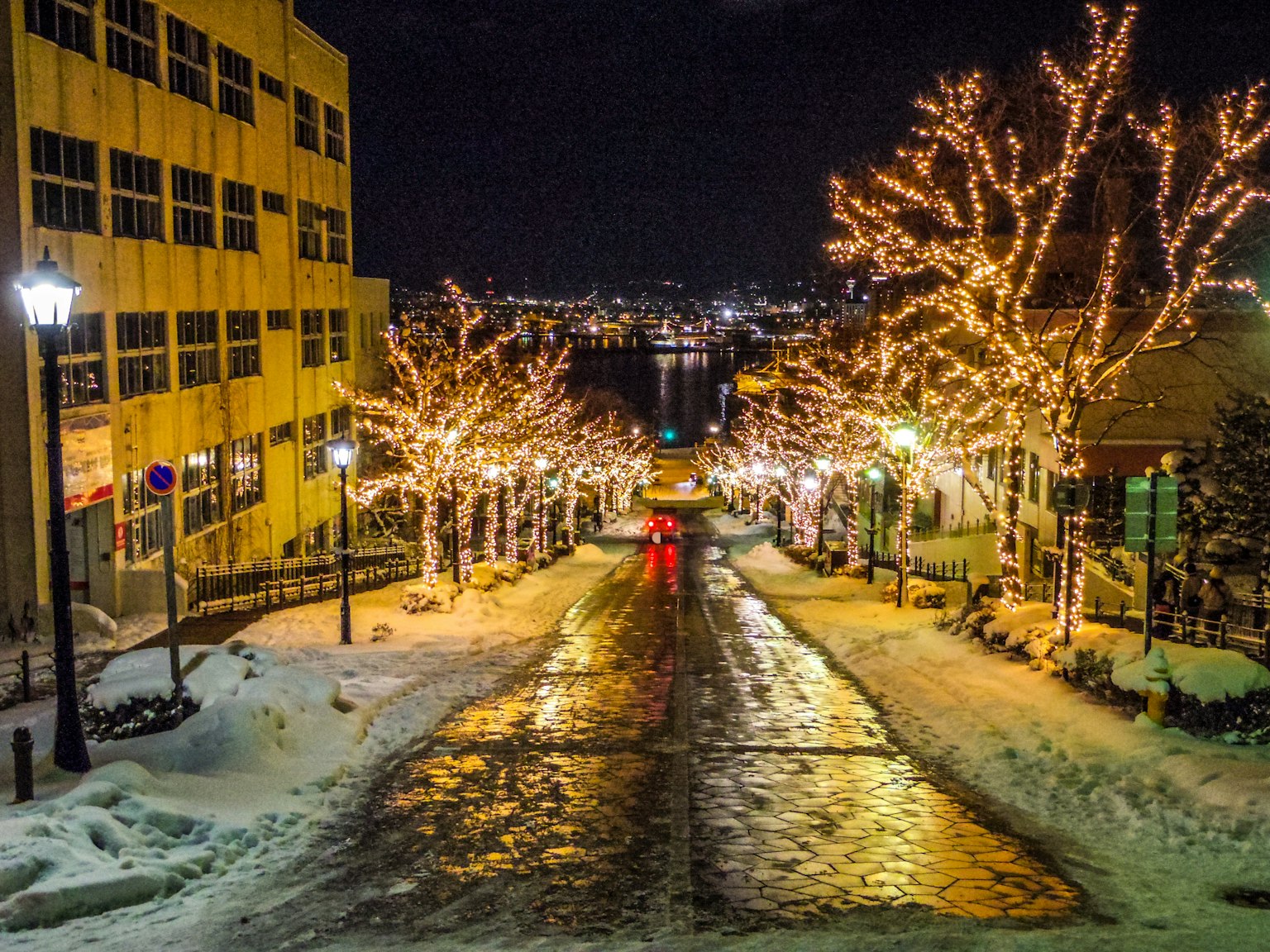 夜间雪覆盖的街道，树木和路灯闪烁