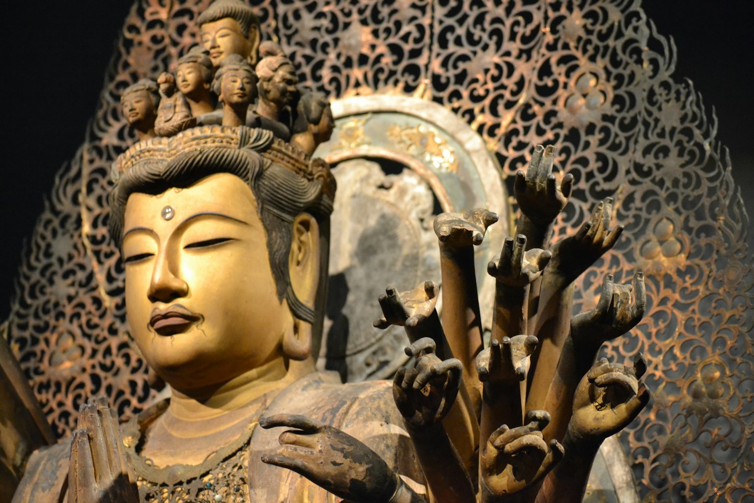 金色观音像被精美雕刻的手和装饰背景包围