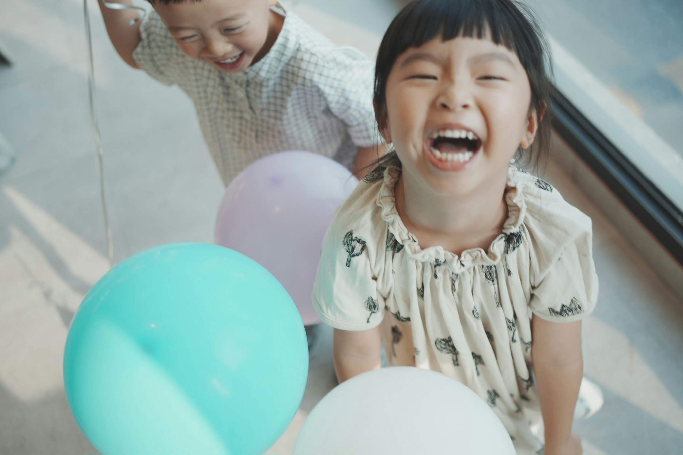 風船を手に笑顔の子どもたちの室内シーン