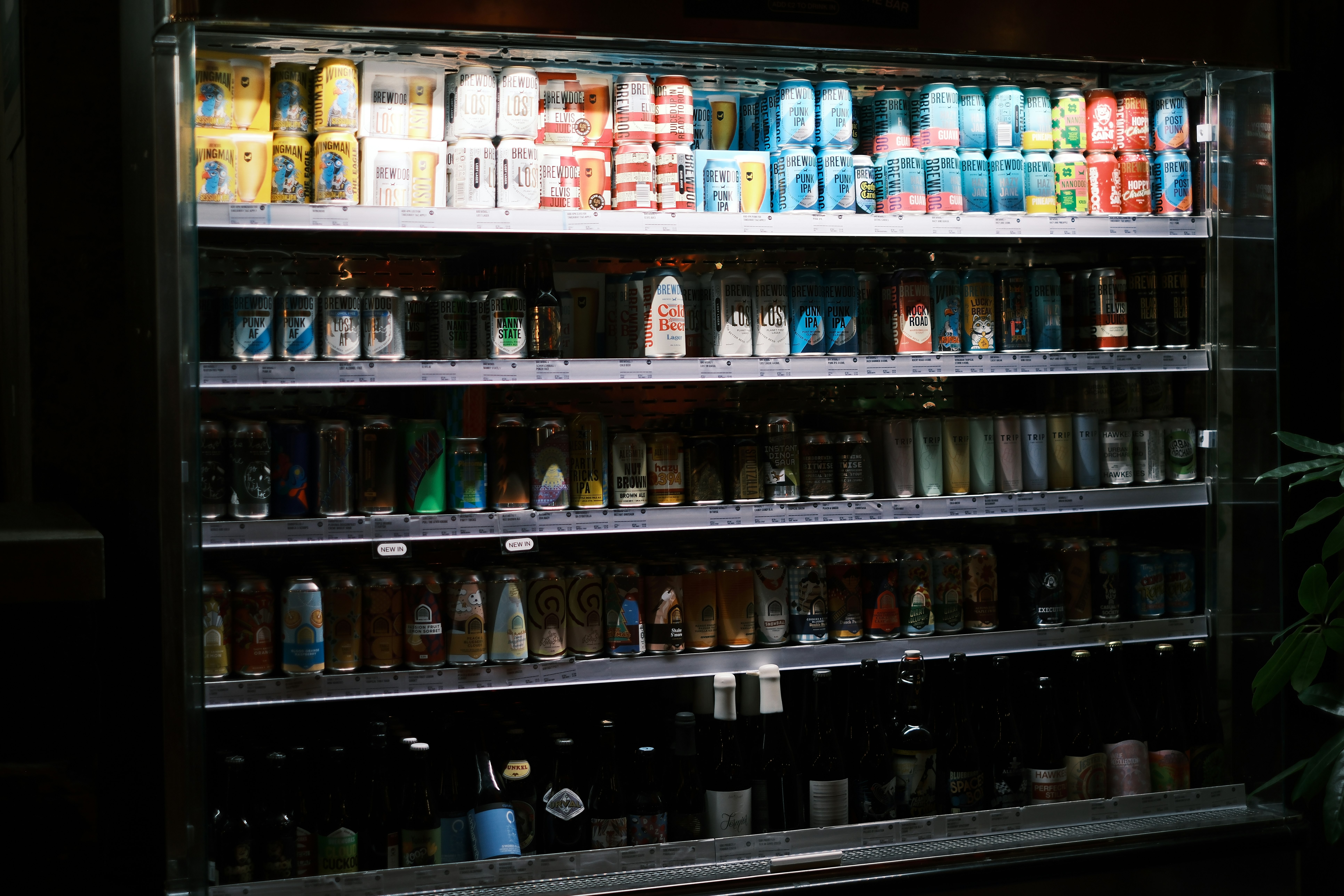 商店冷藏货架上摆满罐头、瓶装与玻璃瓶
