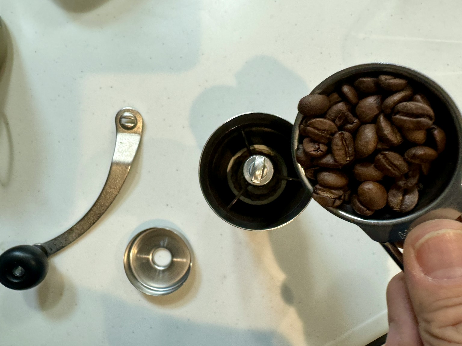 เมล็ดกาแฟในถ้วยตวงเหนือเครื่องบดกาแฟพร้อมเครื่องมือใกล้เคียง