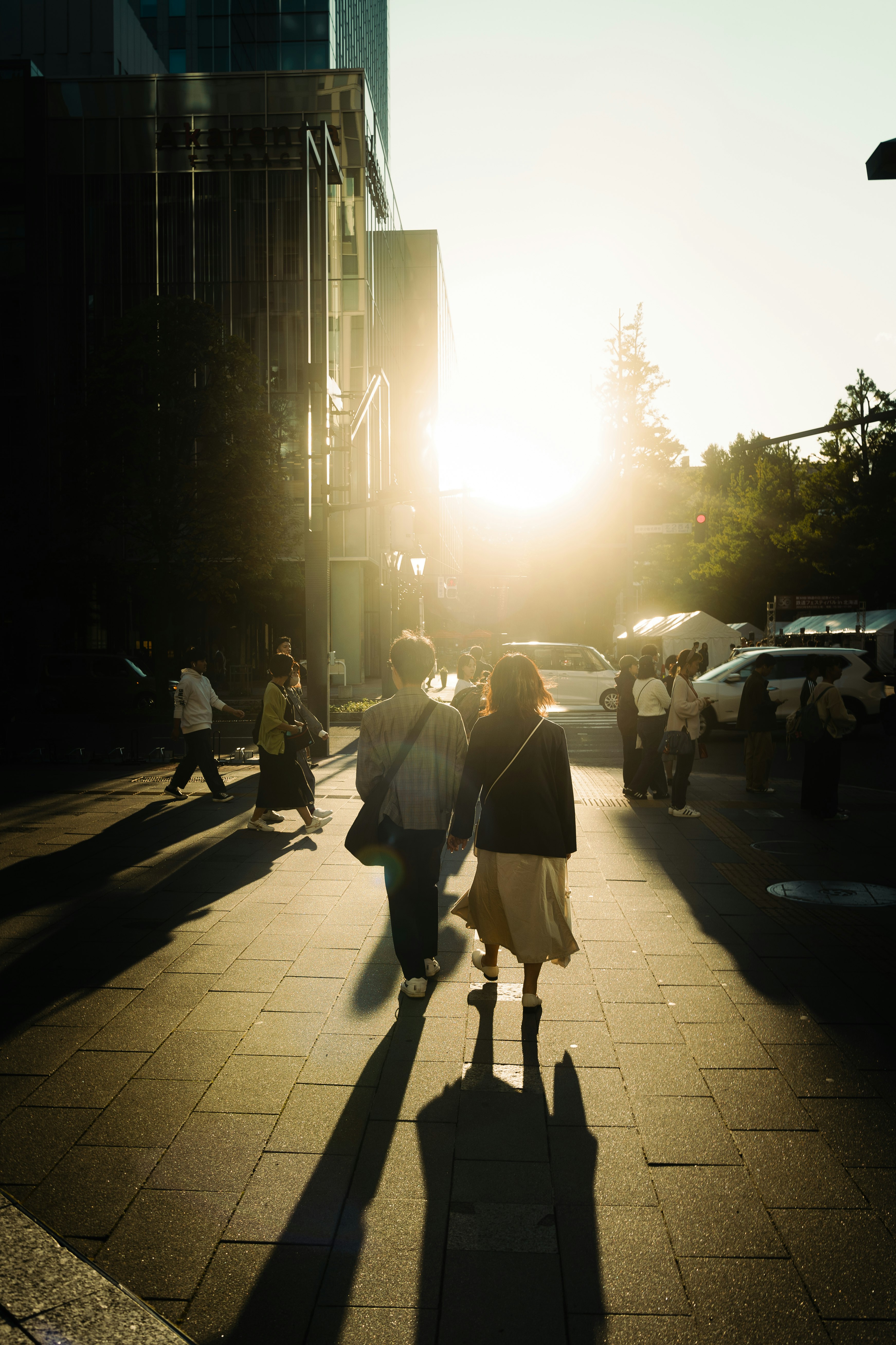 Pedestrians walking along a city street in the sunset glow